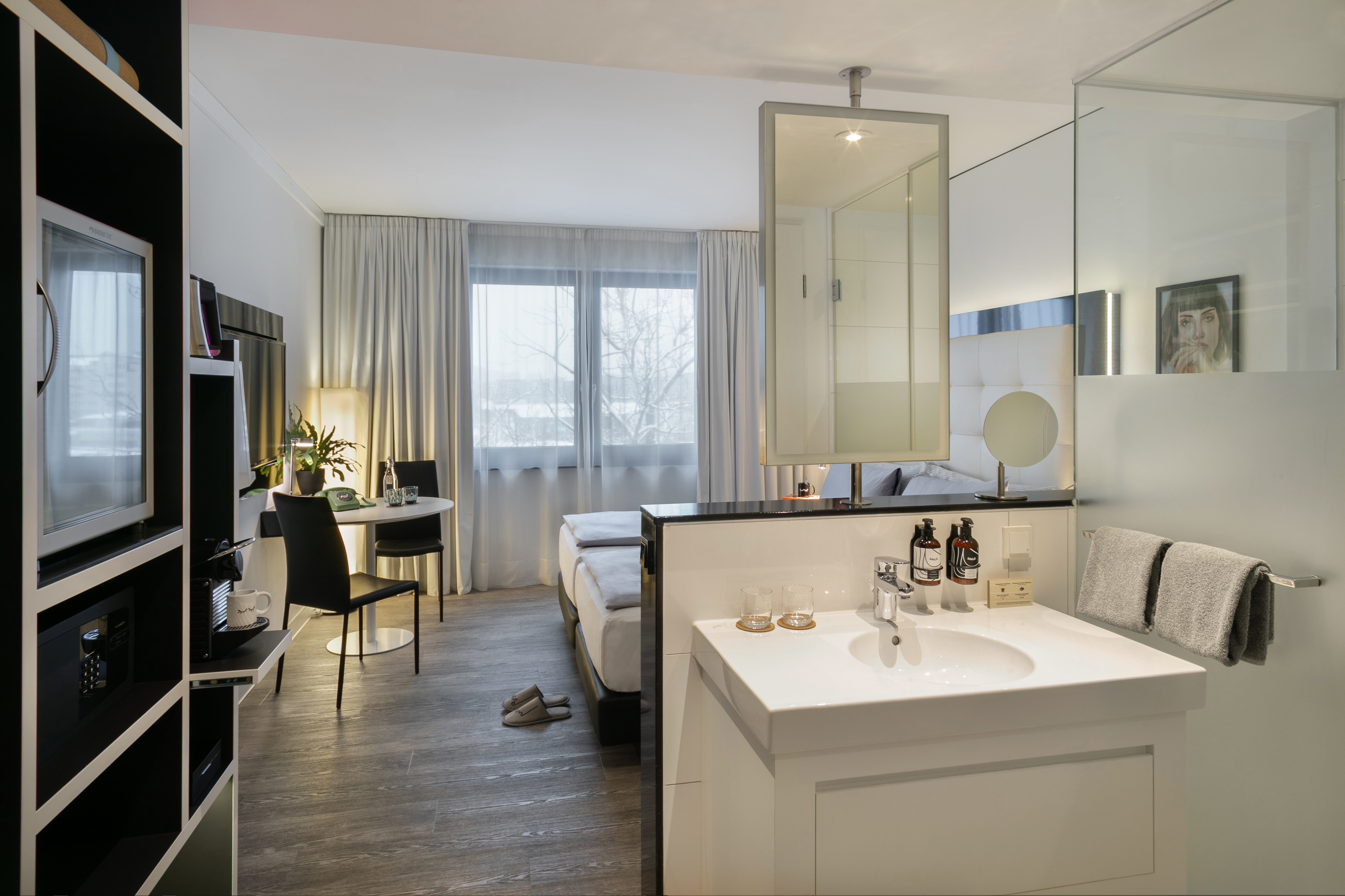 Modern hotel suite with bed, work desk, and integrated bathroom vanity.