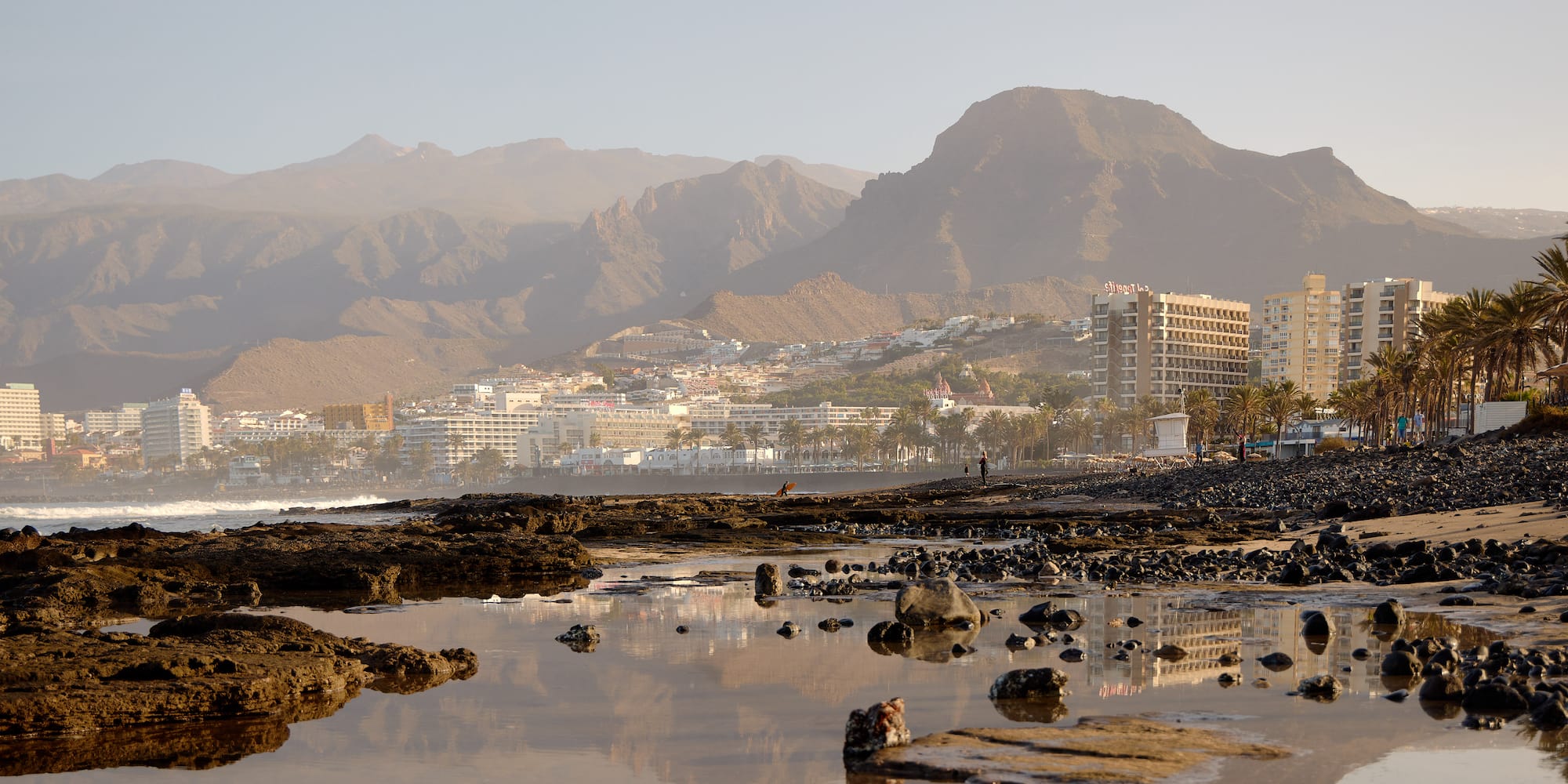 a rocky beach with mountains in the background
