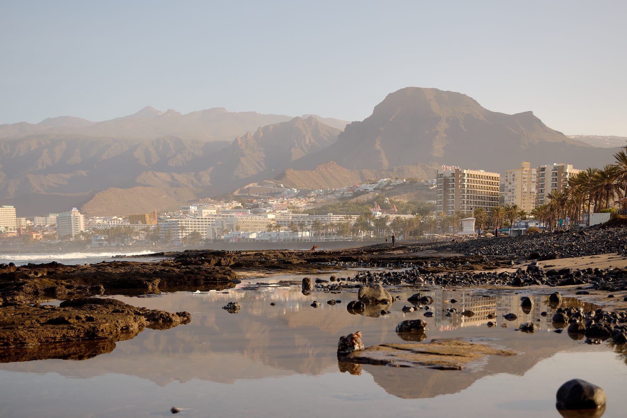 a rocky beach with mountains in the background