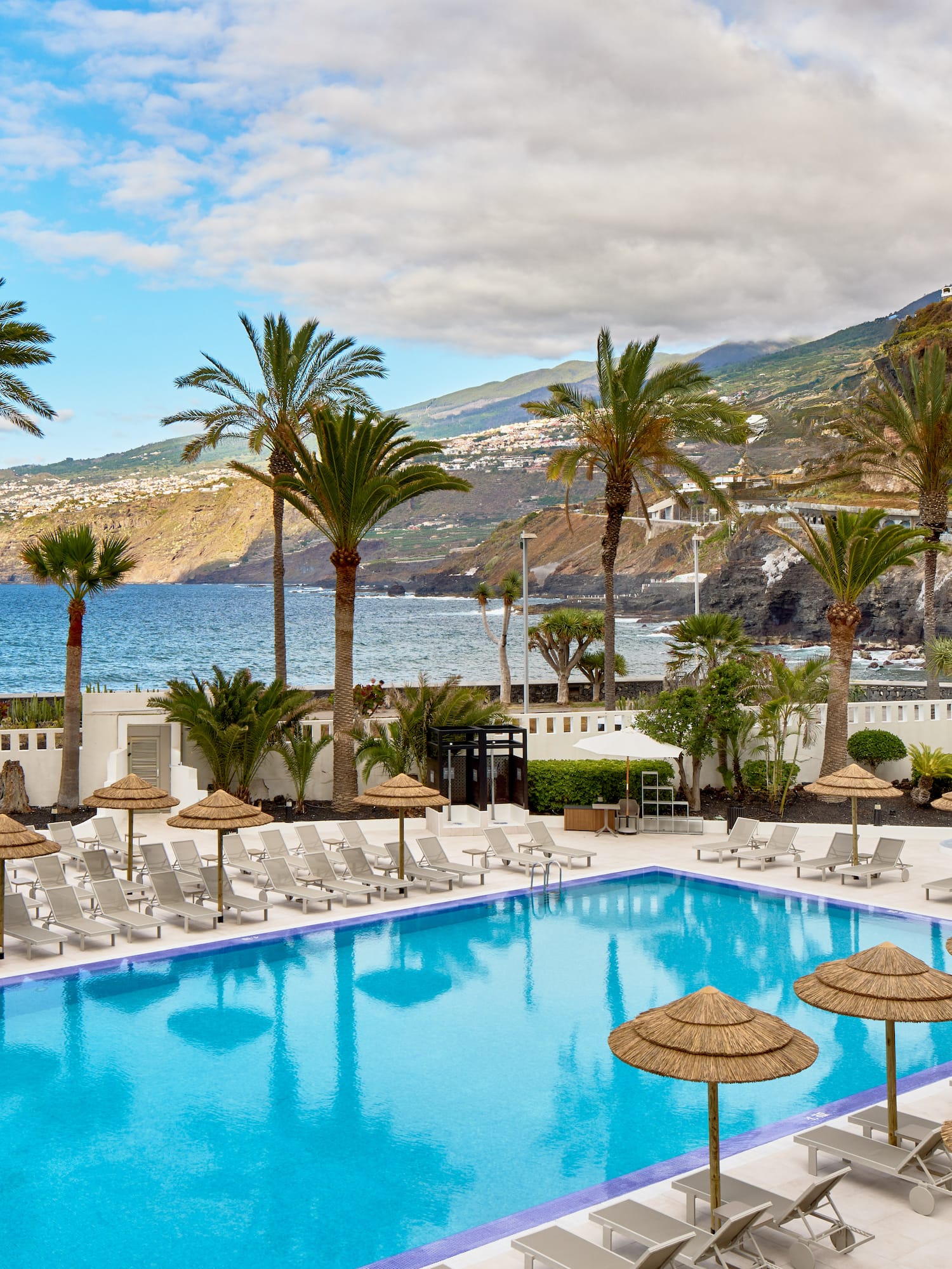 a pool with umbrellas and chairs by the water