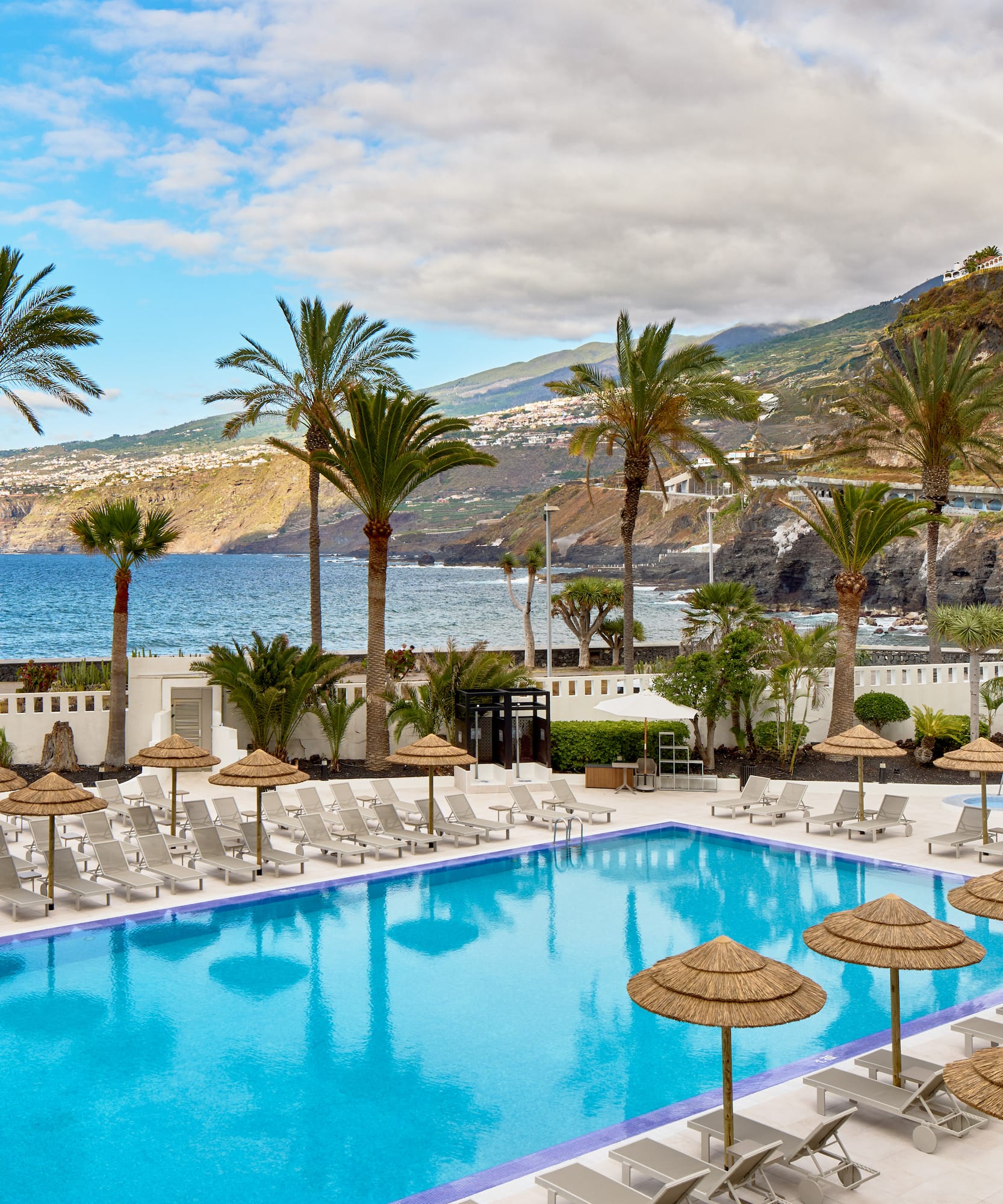 a pool with umbrellas and chairs by the water