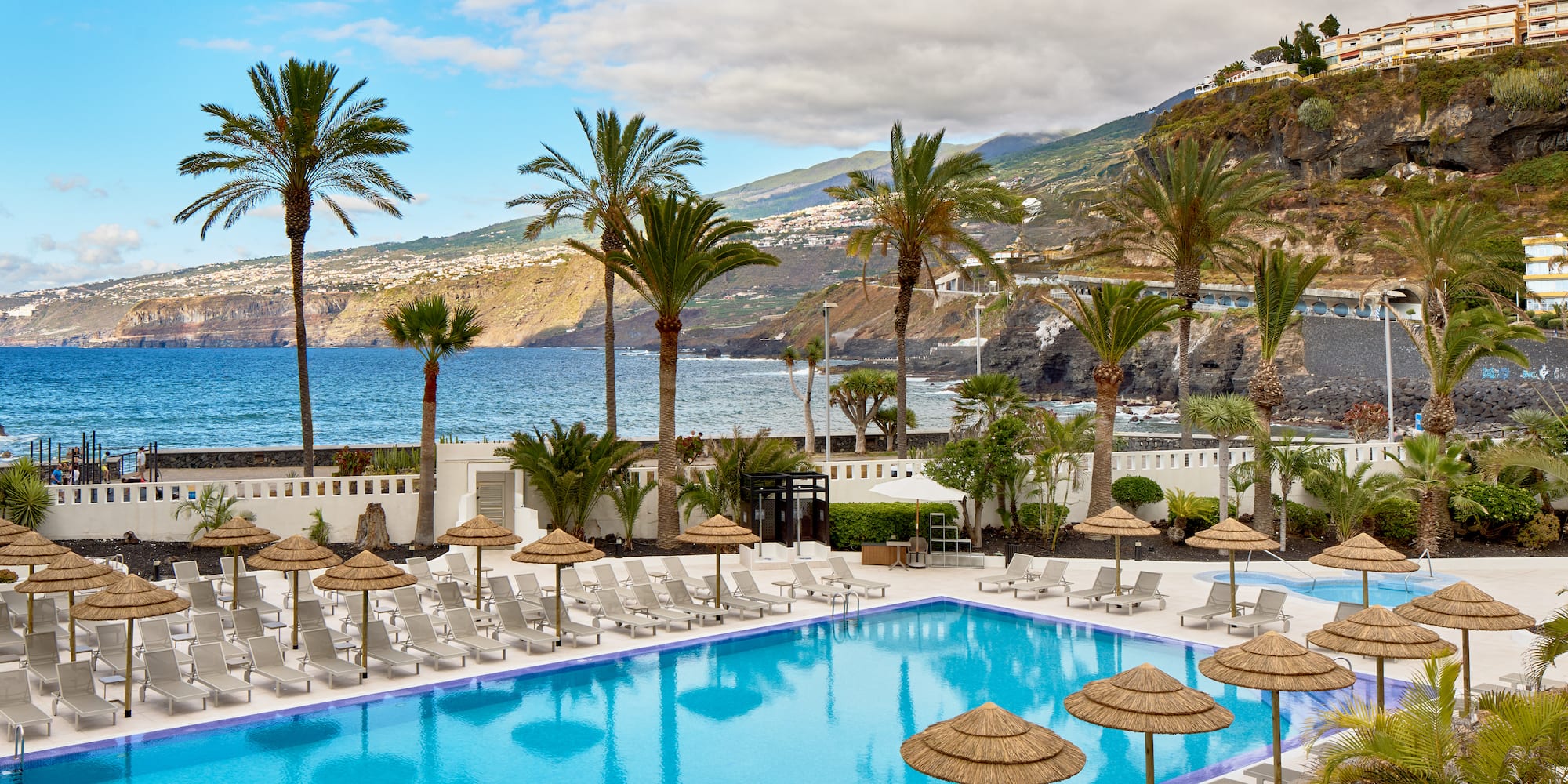 a pool with umbrellas and chairs by the water