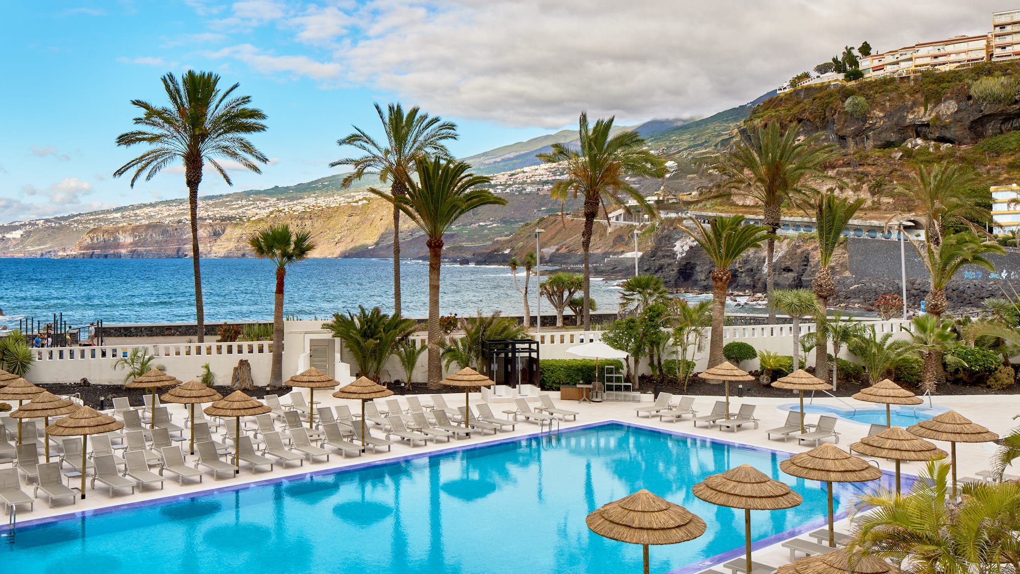 a pool with umbrellas and chairs by the water