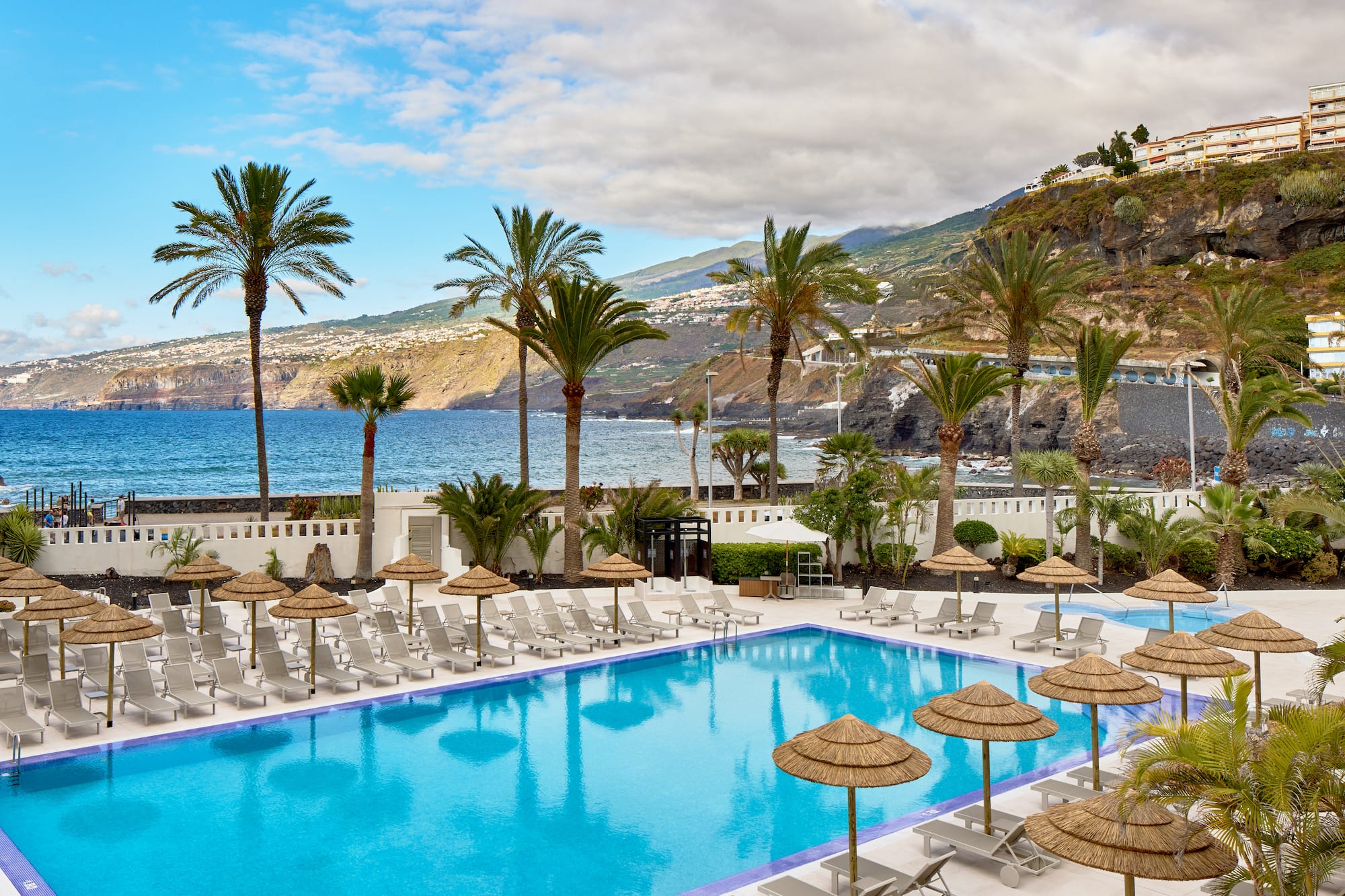 a pool with umbrellas and chairs by the water