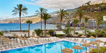 a pool with umbrellas and chairs by the water