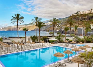 a pool with umbrellas and chairs by the water