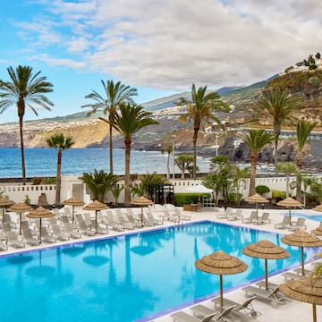 a pool with umbrellas and chairs by the water