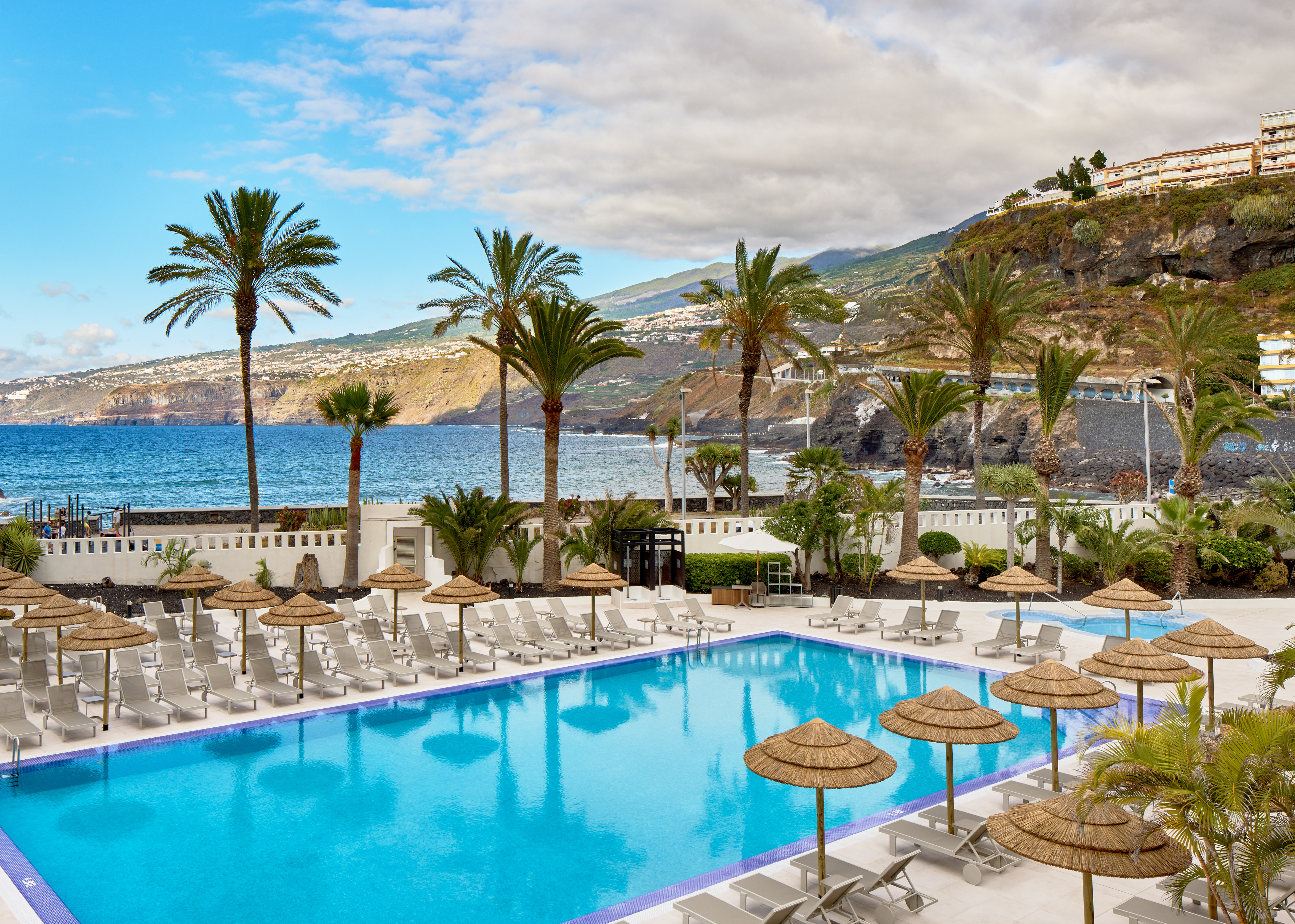 a pool with umbrellas and chairs by the water