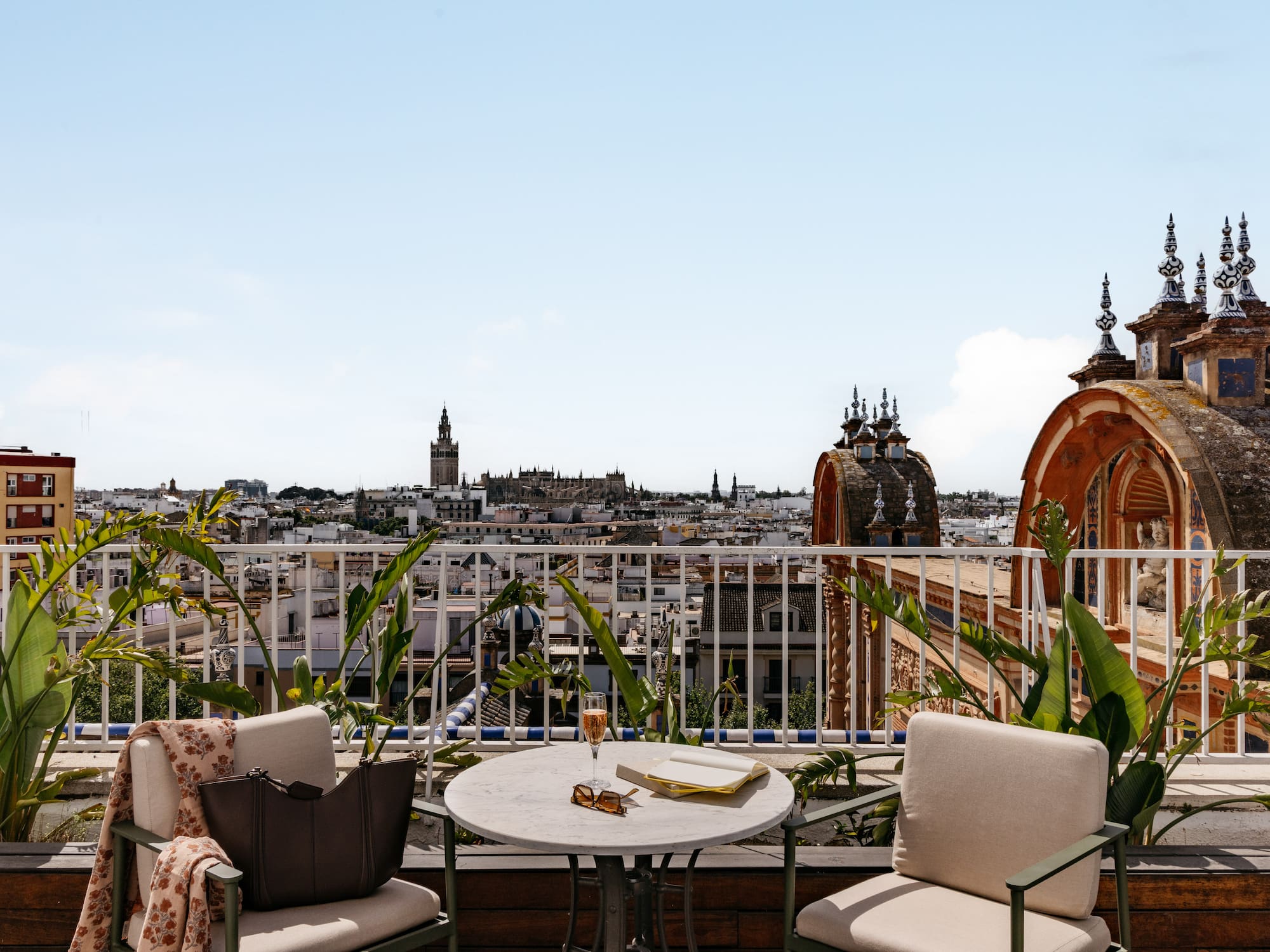 Seville rooftop terrace with Giralda tower, city view, table, chairs.