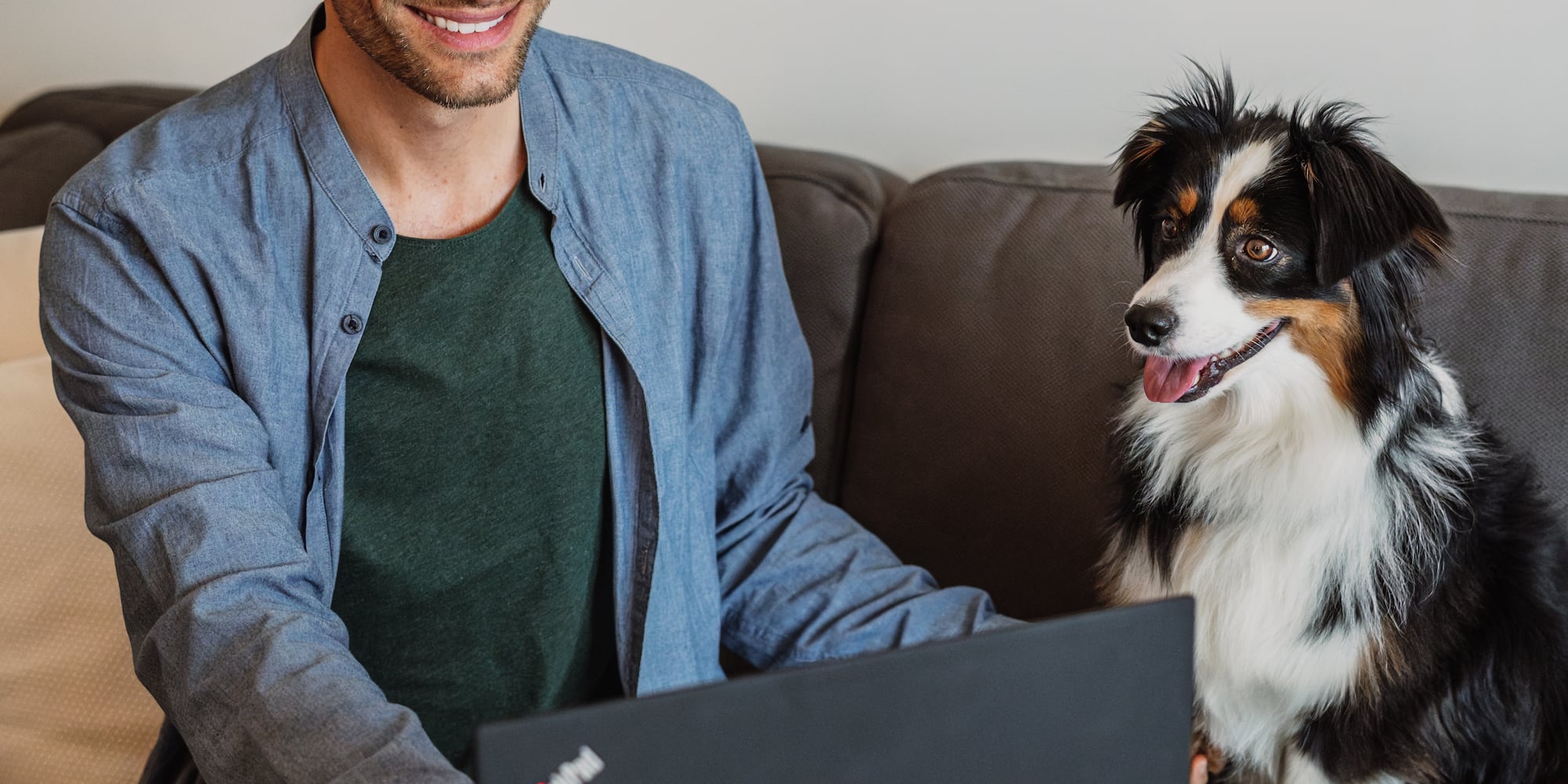 a man sitting at a table with a laptop and a dog