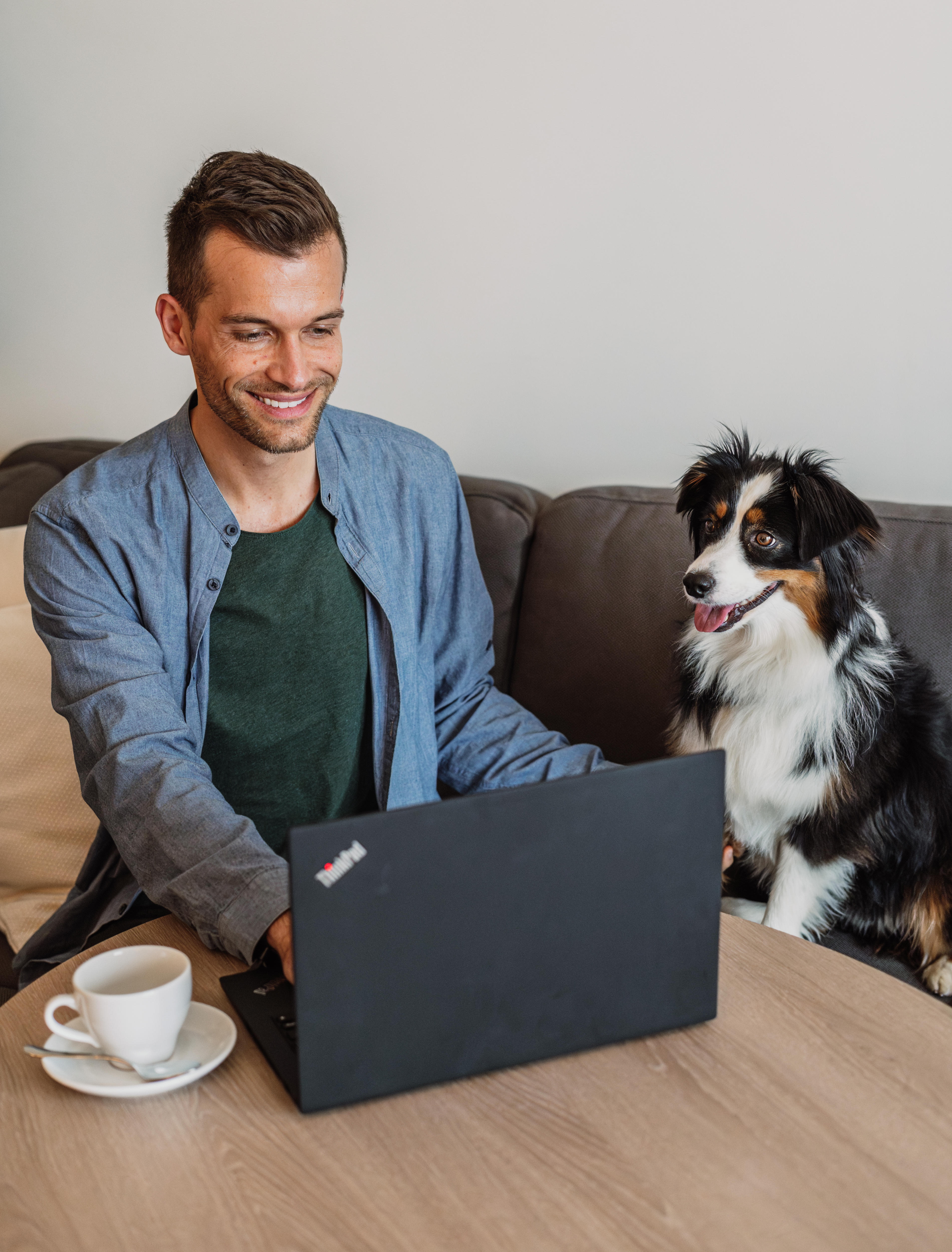 Man on laptop with Australian Shepherd dog, working from home.
