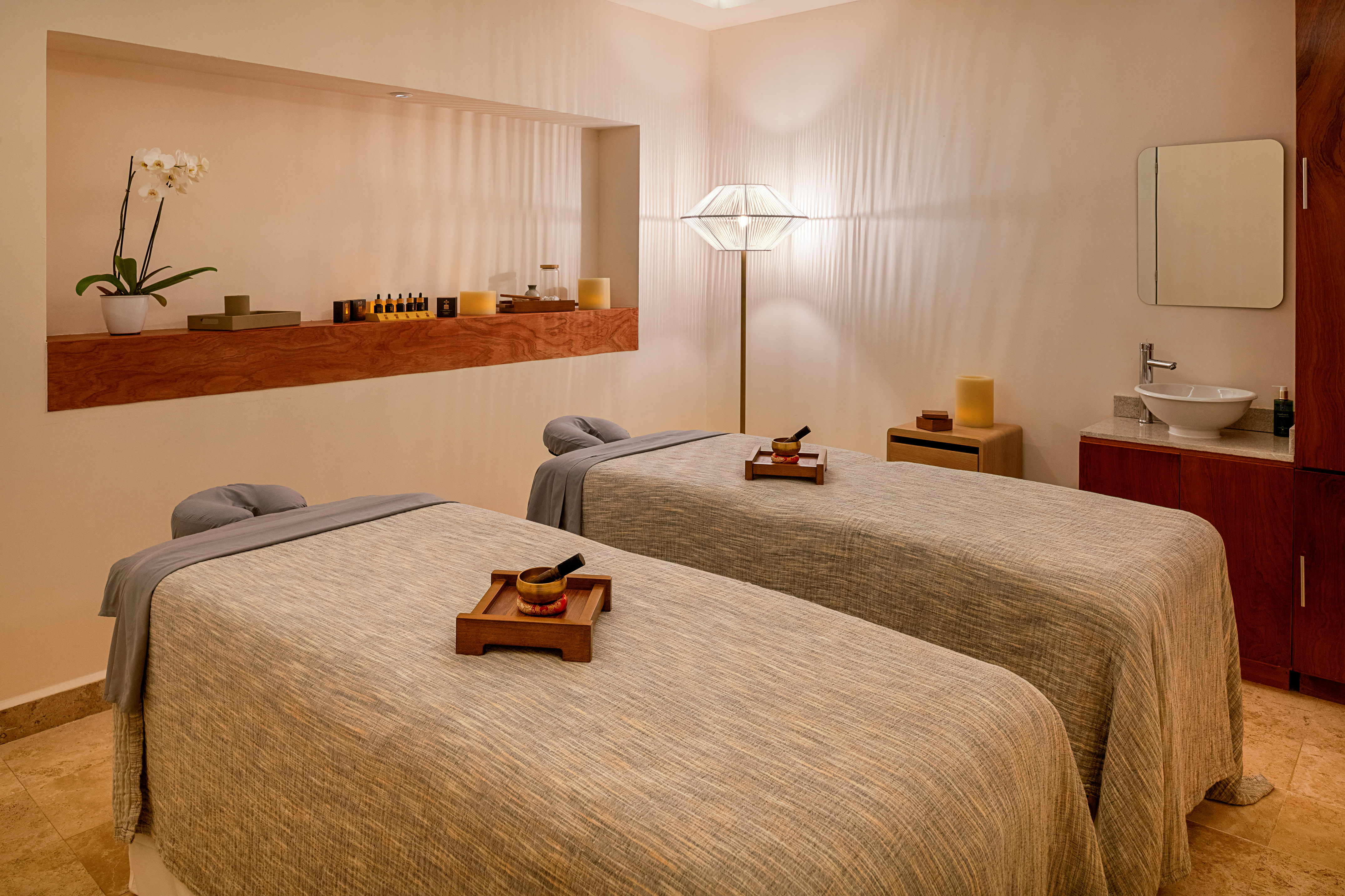 Serene spa room with two massage tables, warm lighting, and wellness accents.