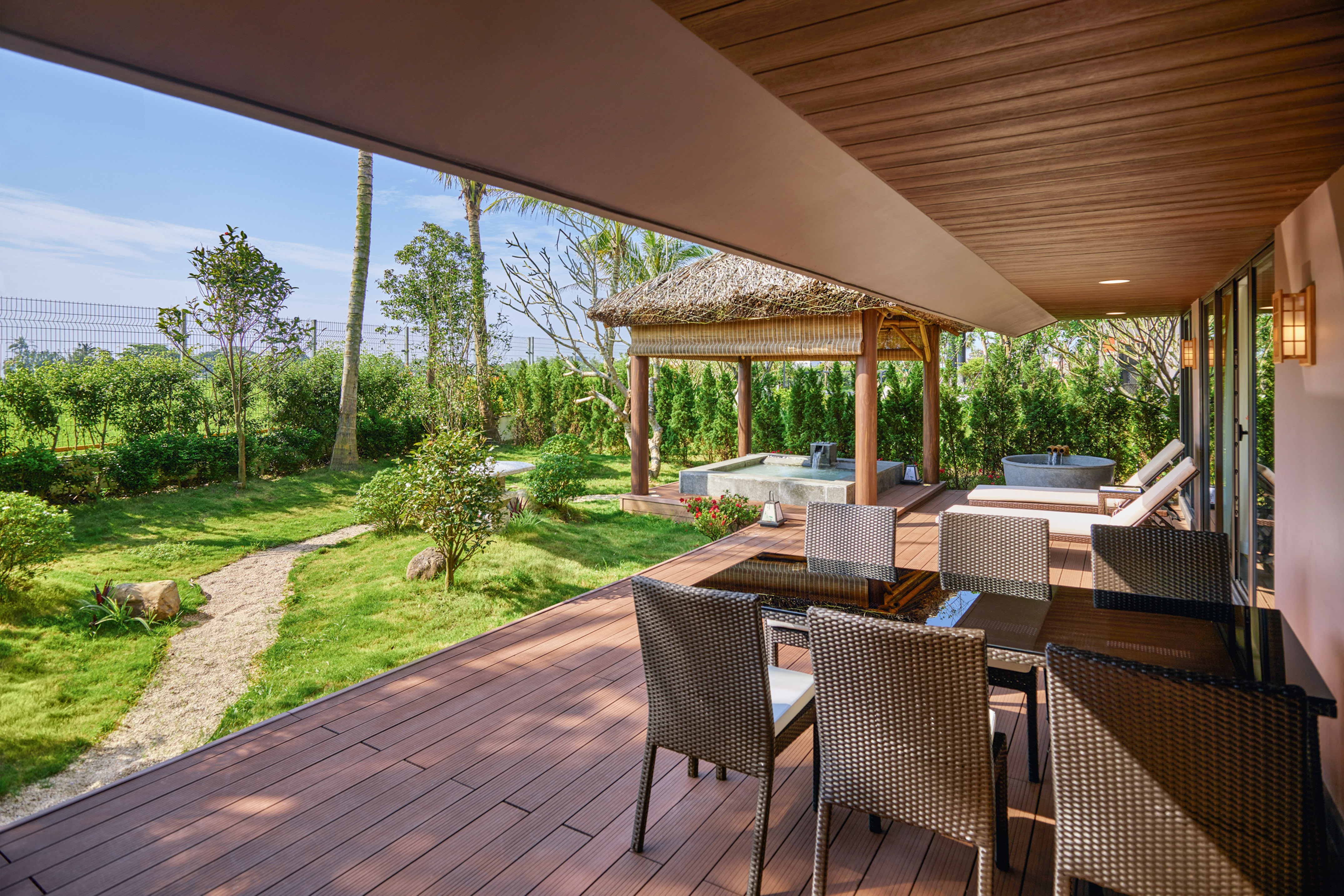 Tropical patio deck with outdoor dining, lush garden, gazebo, and hot tub.