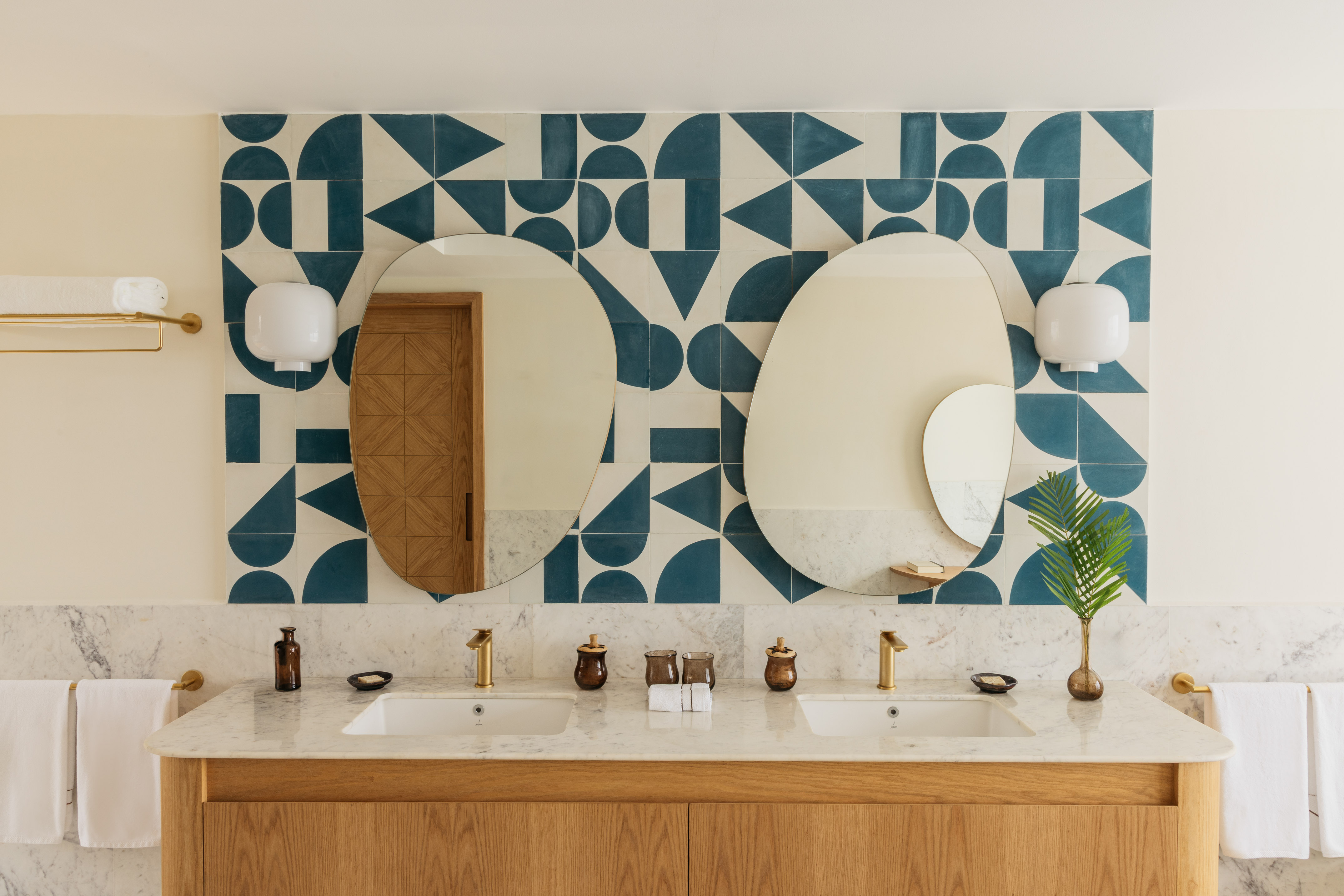 Double bathroom vanity, wood, marble, blue geometric tile backsplash.