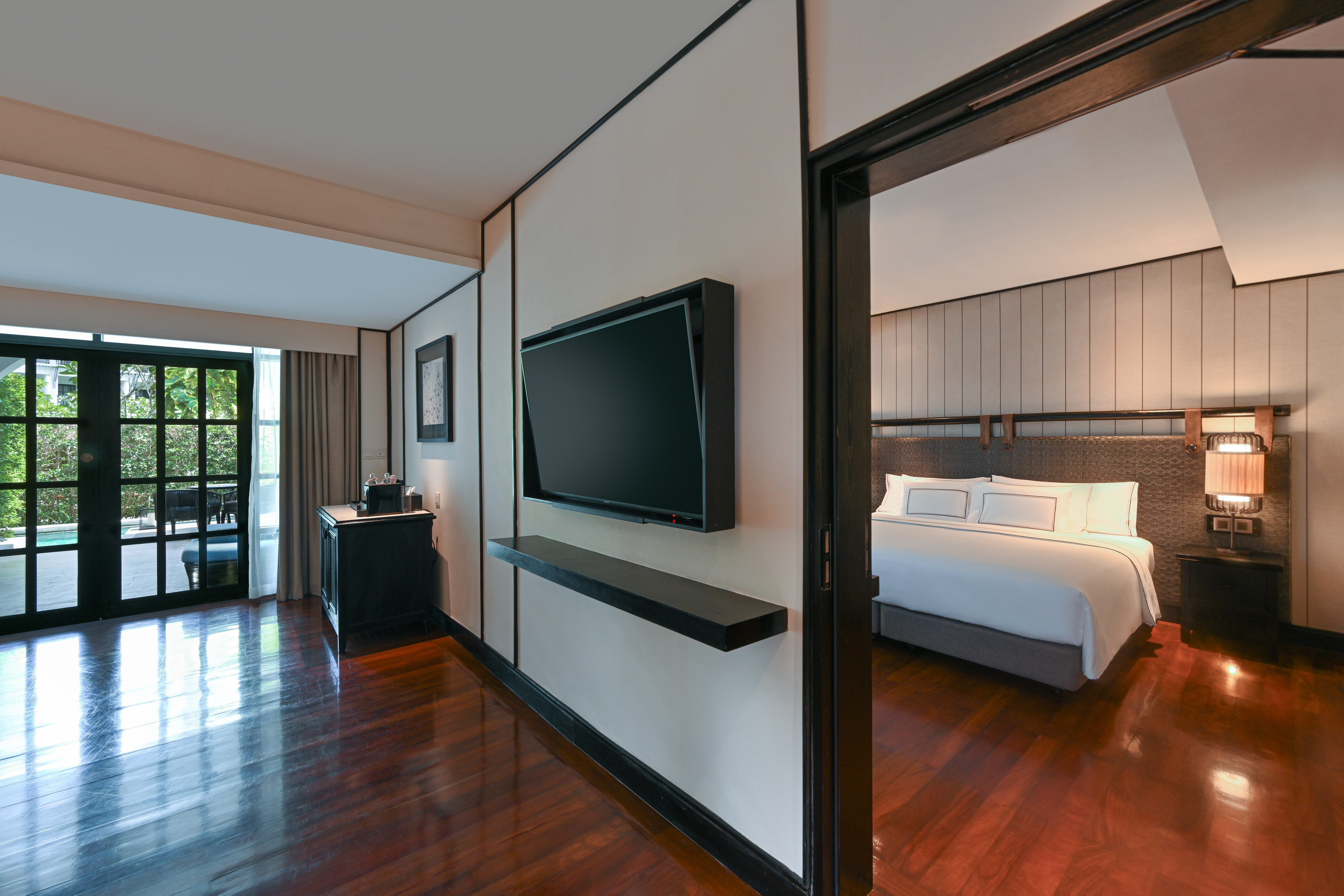 Luxury hotel suite: TV, dark wood floors, bedroom, and outdoor patio.