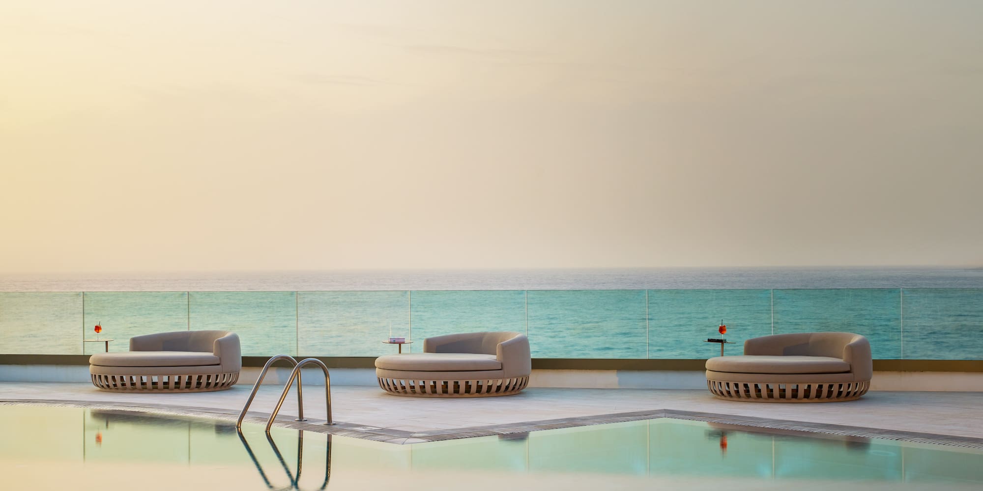 a pool with chairs and a body of water