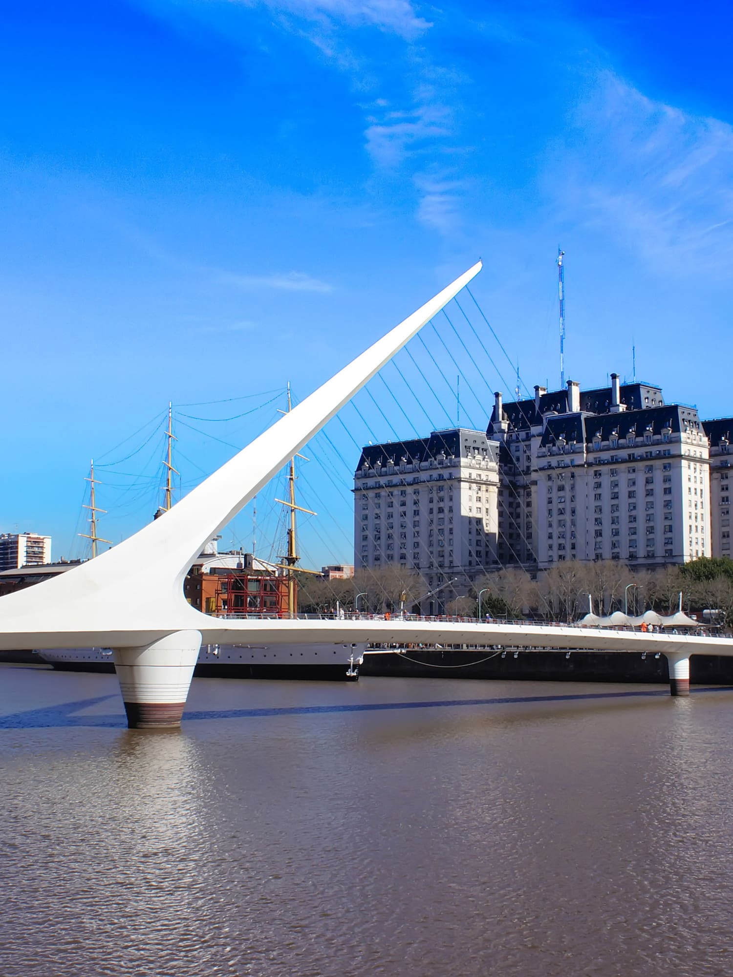 a bridge over water with a large building in the background