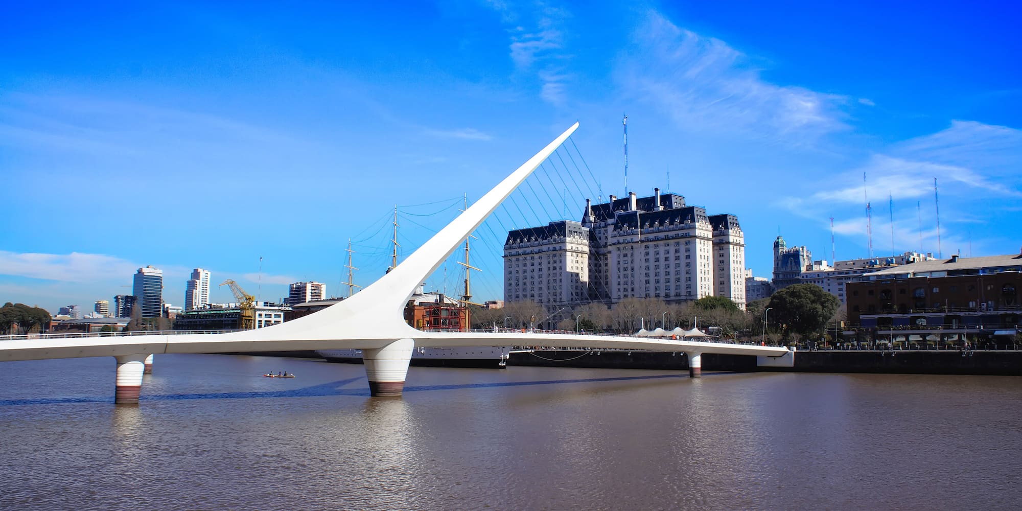 a bridge over water with a large building in the background