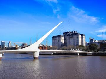 a bridge over water with a large building in the background