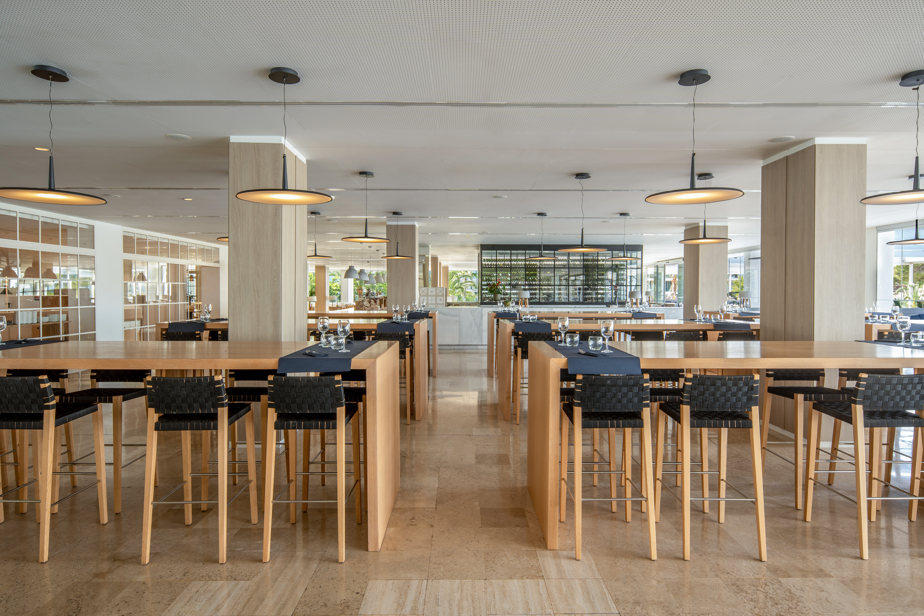 Modern restaurant interior with wooden high tables and black bar stools.