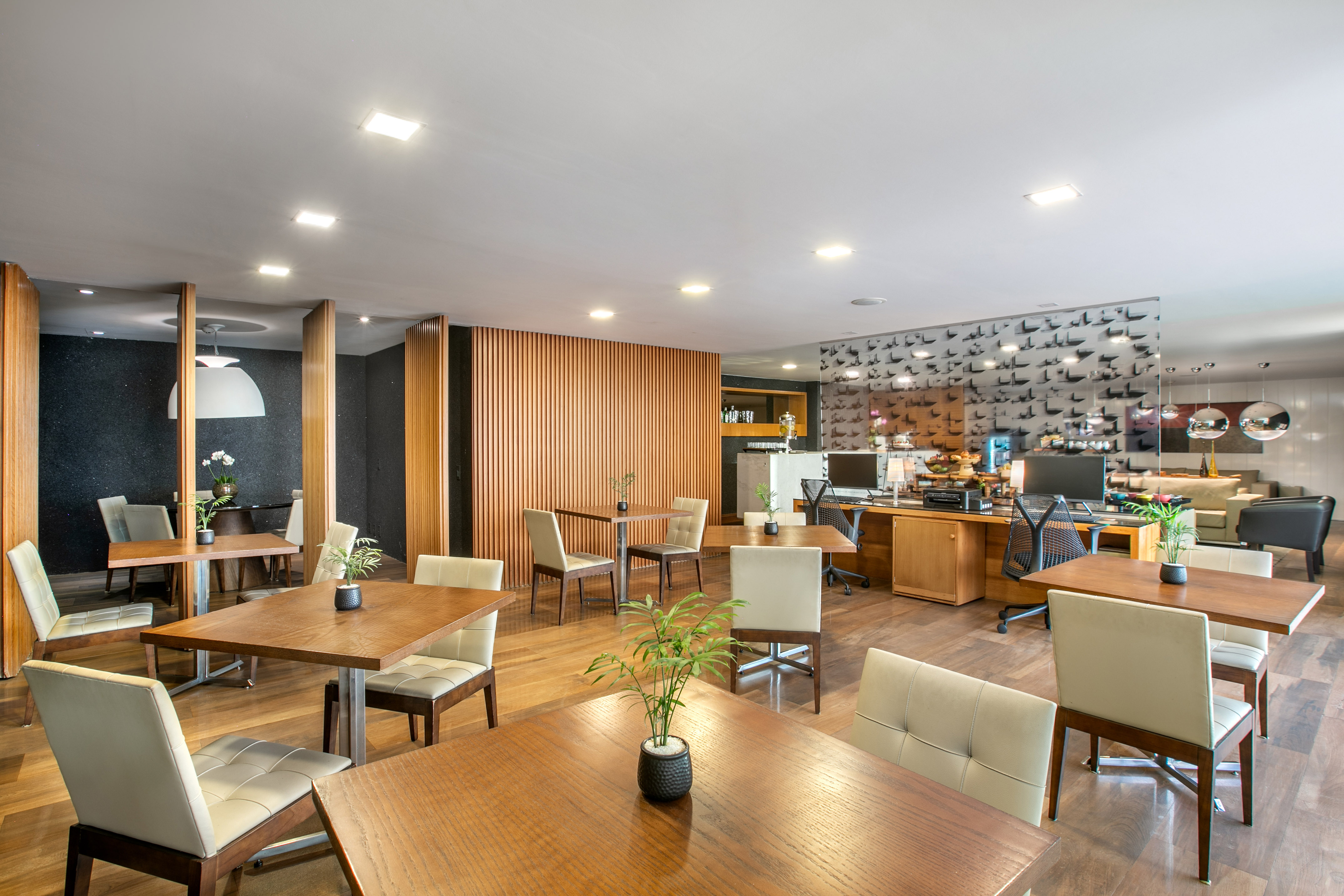 Modern lounge interior with wooden tables, cream chairs, and slatted wood decor.