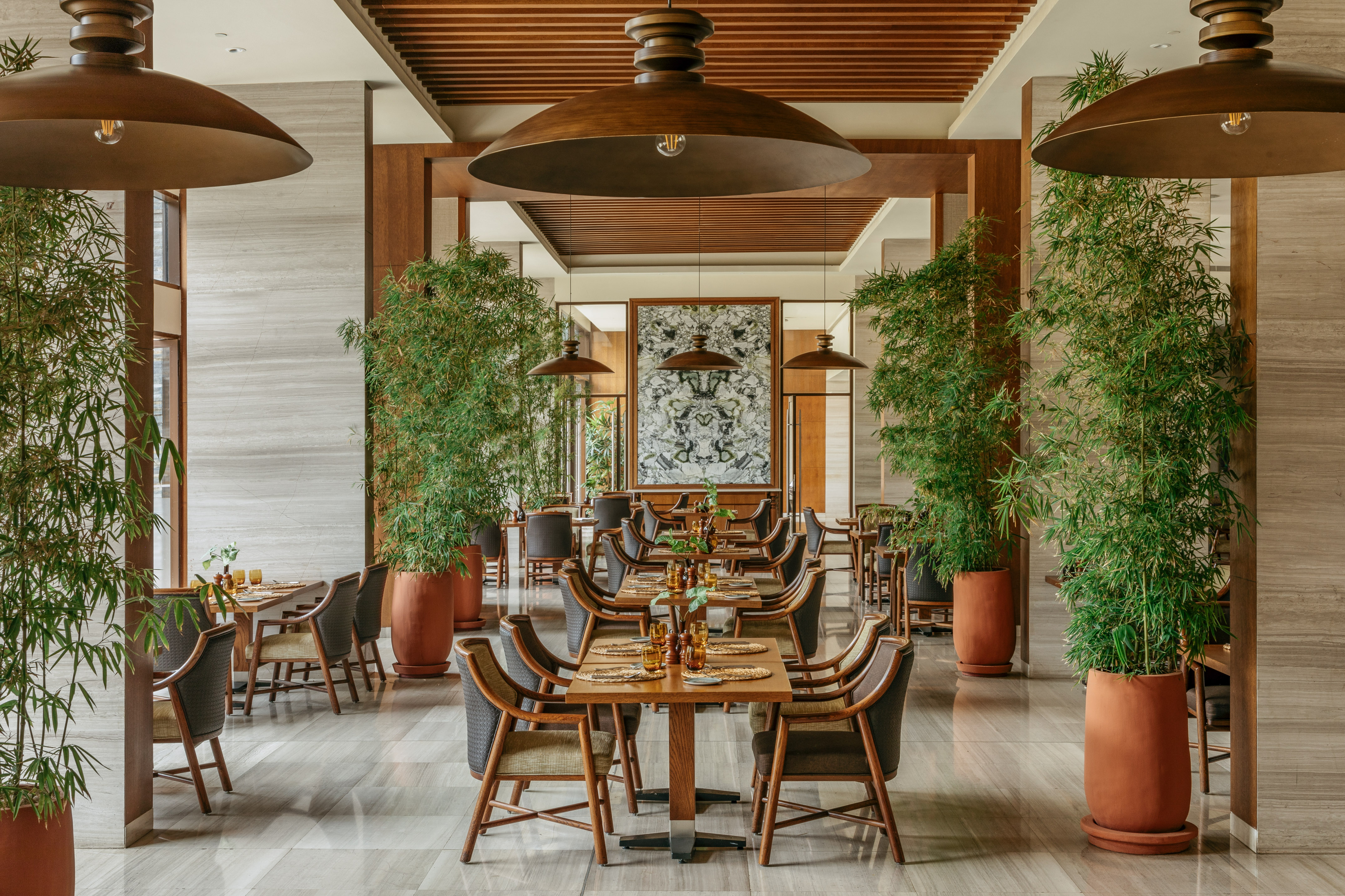 Elegant restaurant interior with wooden tables, bamboo plants, and large dome lights.