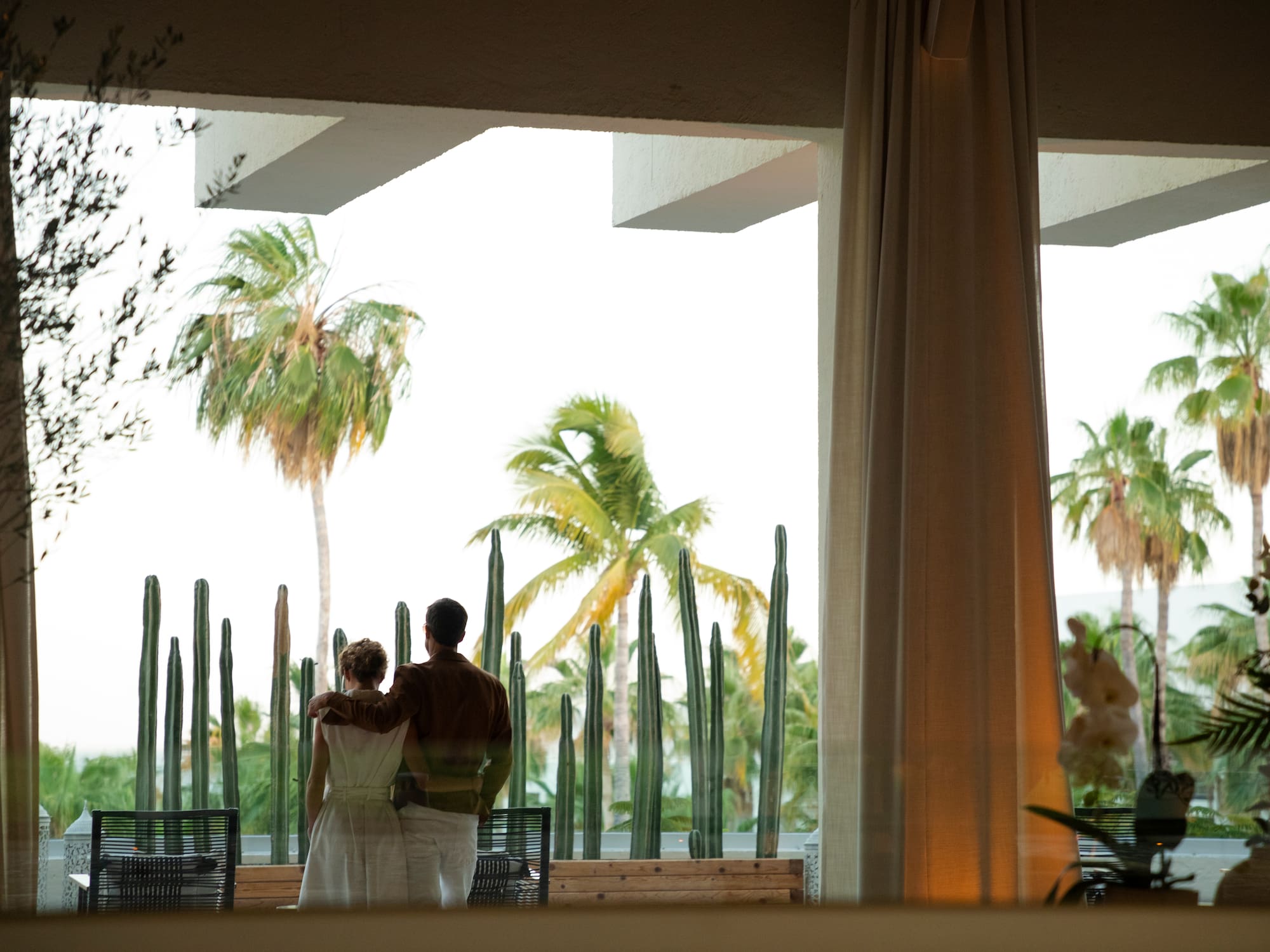 a man and woman standing in front of a cactus