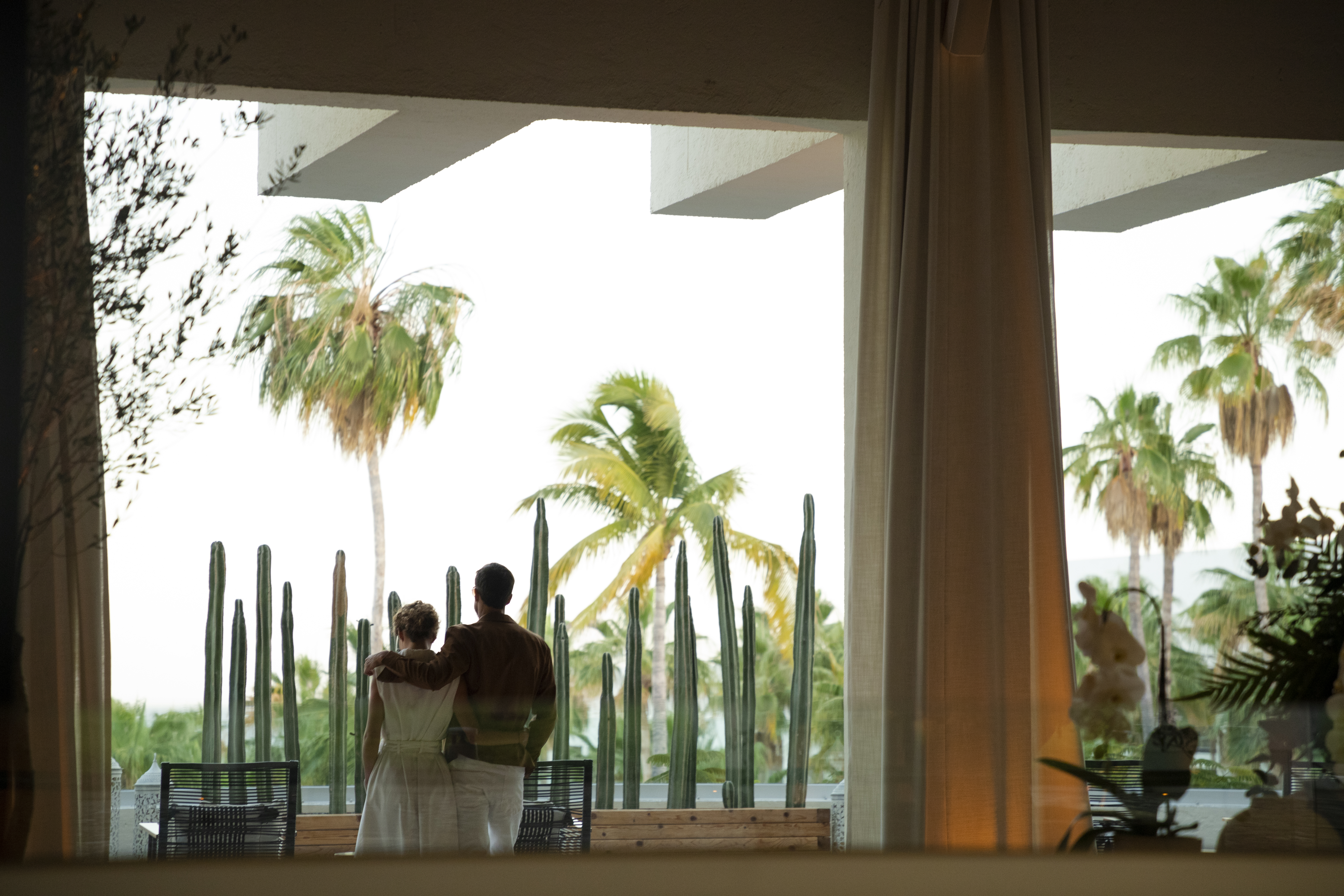 a man and woman standing in front of a cactus