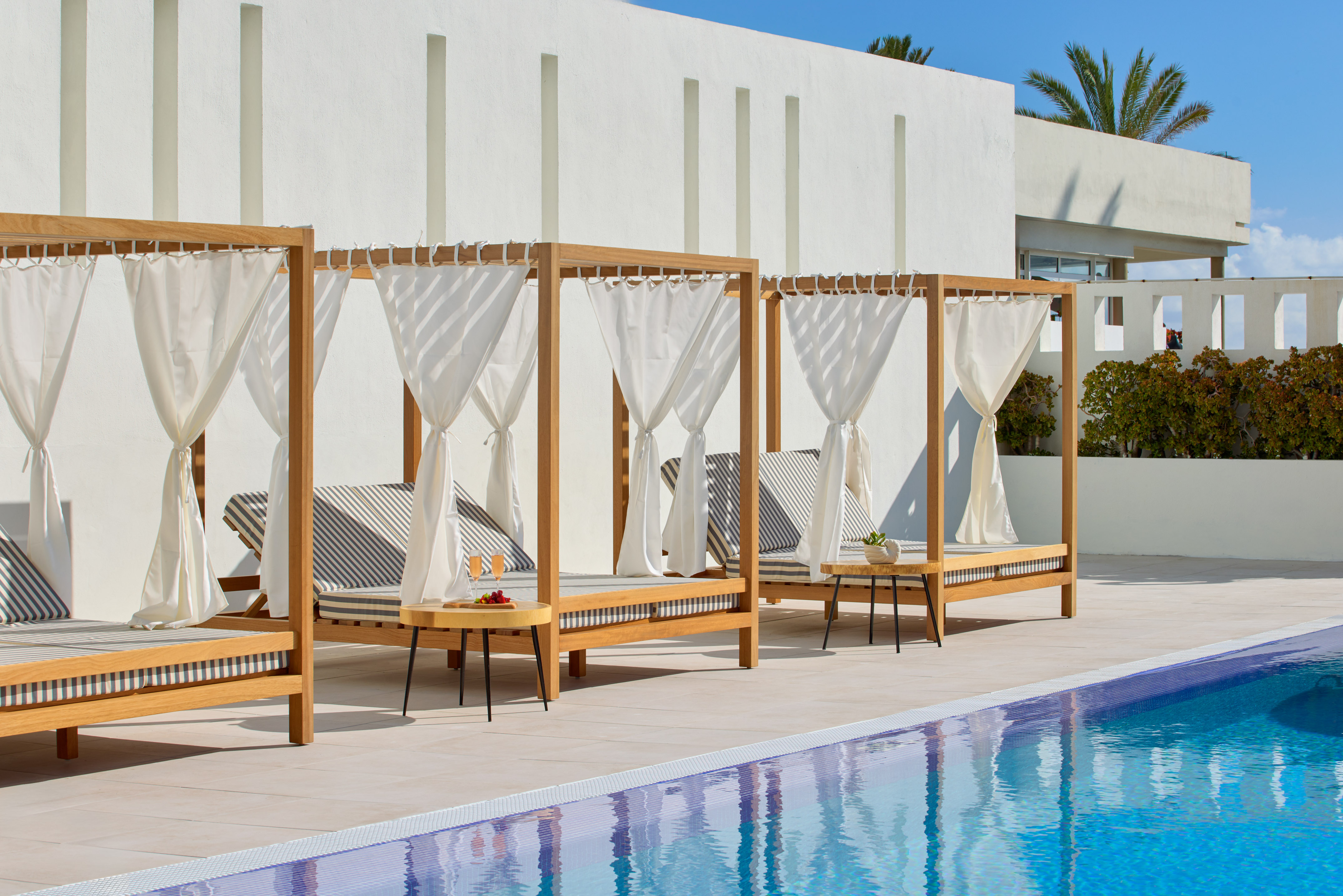 Luxury resort cabanas by pool with white drapes and striped daybeds.
