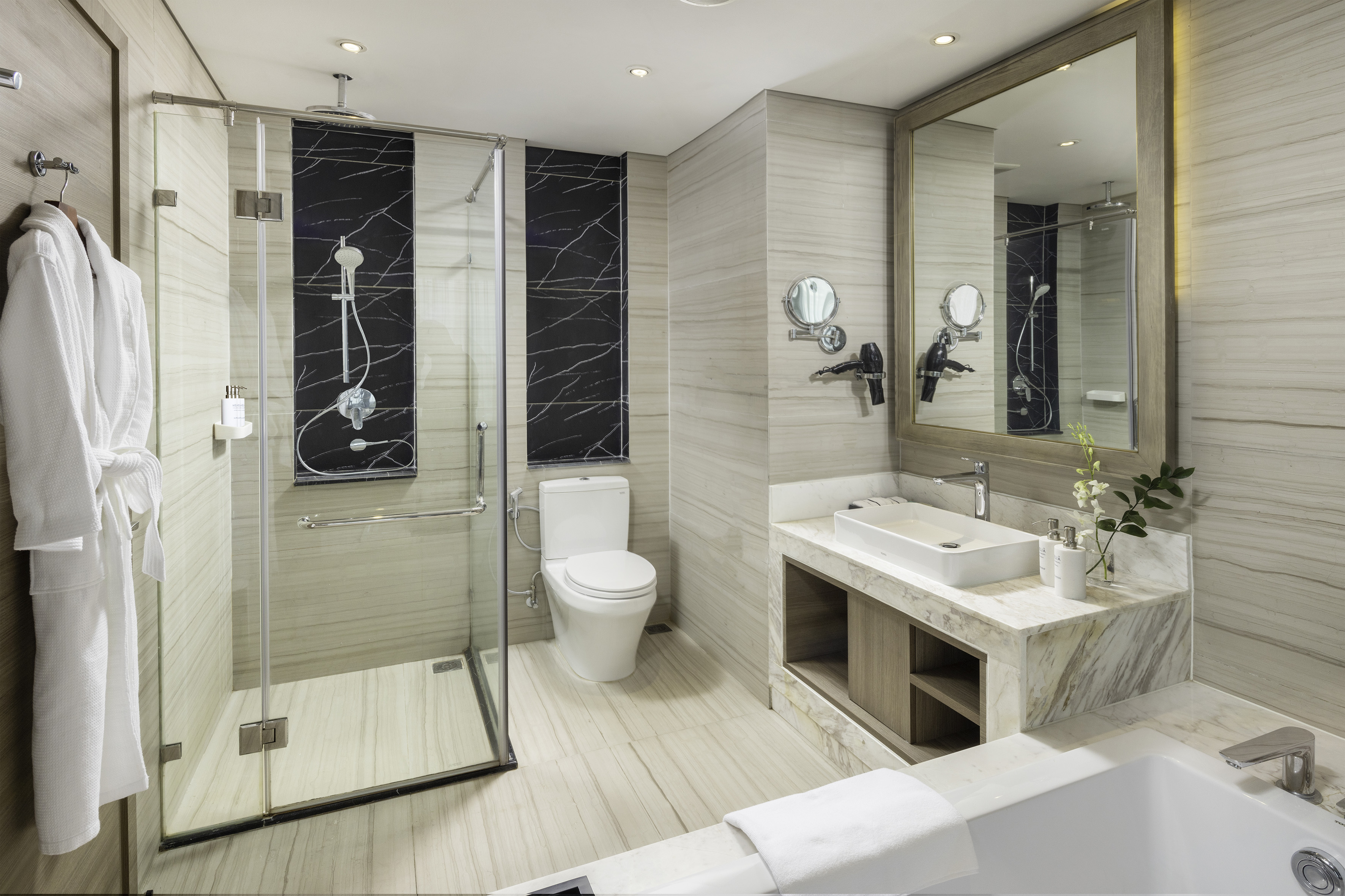 Modern bathroom with glass shower, white toilet, vanity, and bathtub.