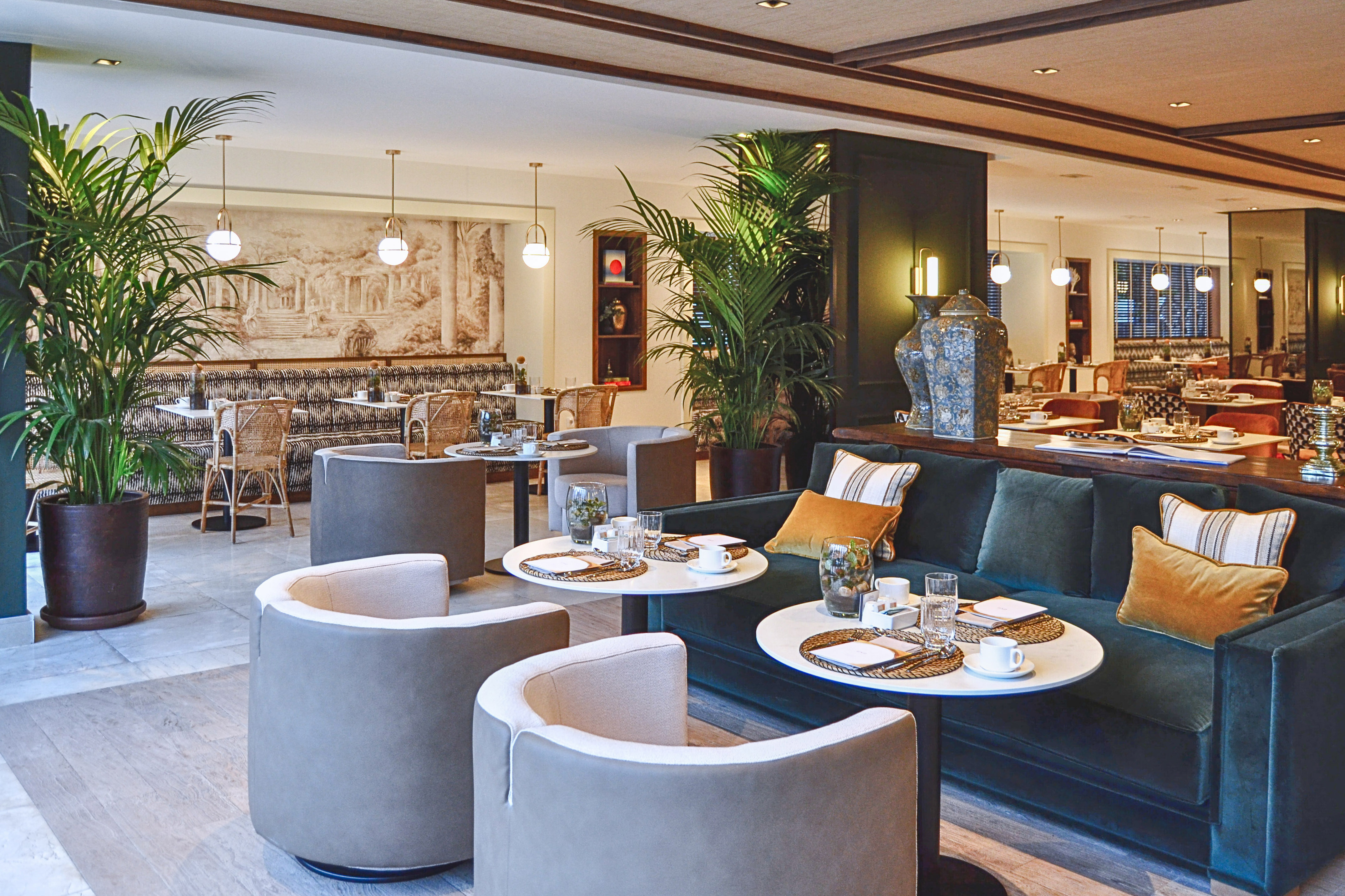 Stylish hotel lounge dining with velvet sofa, modern seating, and plants.