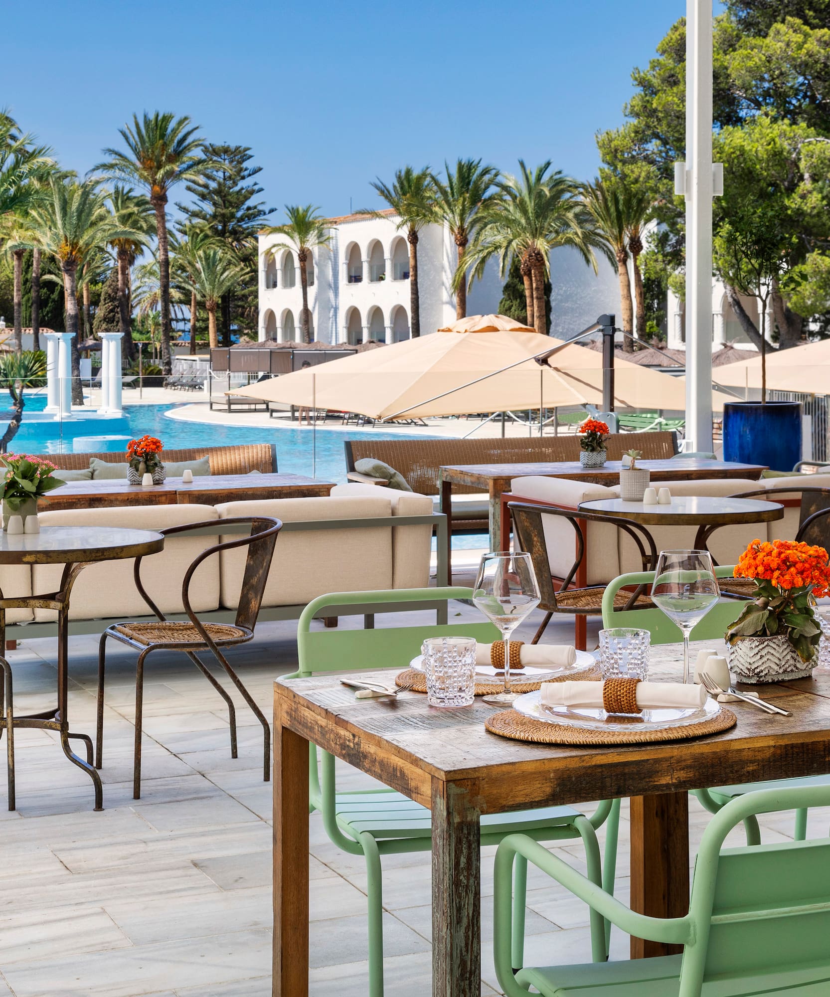 tables and chairs outside with a pool in the background
