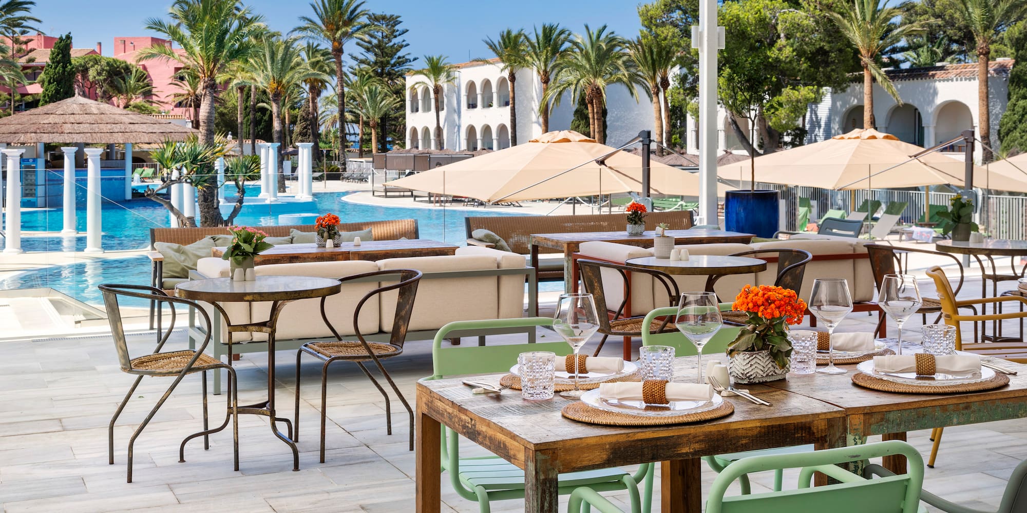 tables and chairs outside with a pool in the background