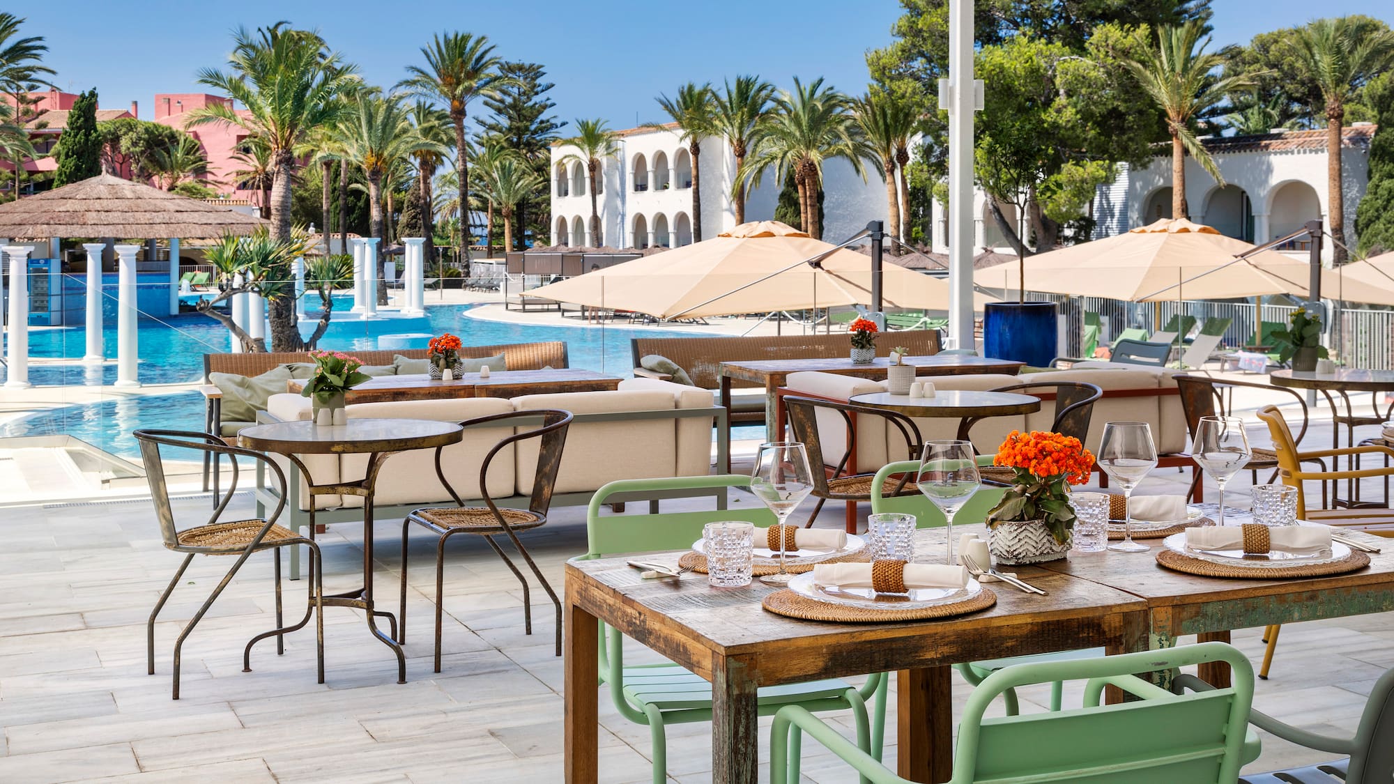 tables and chairs outside with a pool in the background