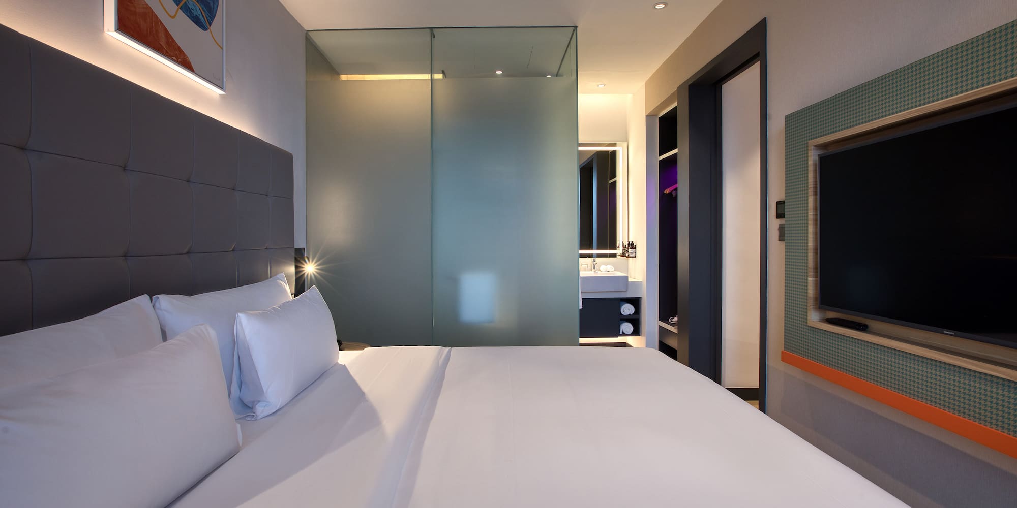 a bed with white sheets and a glass shower door