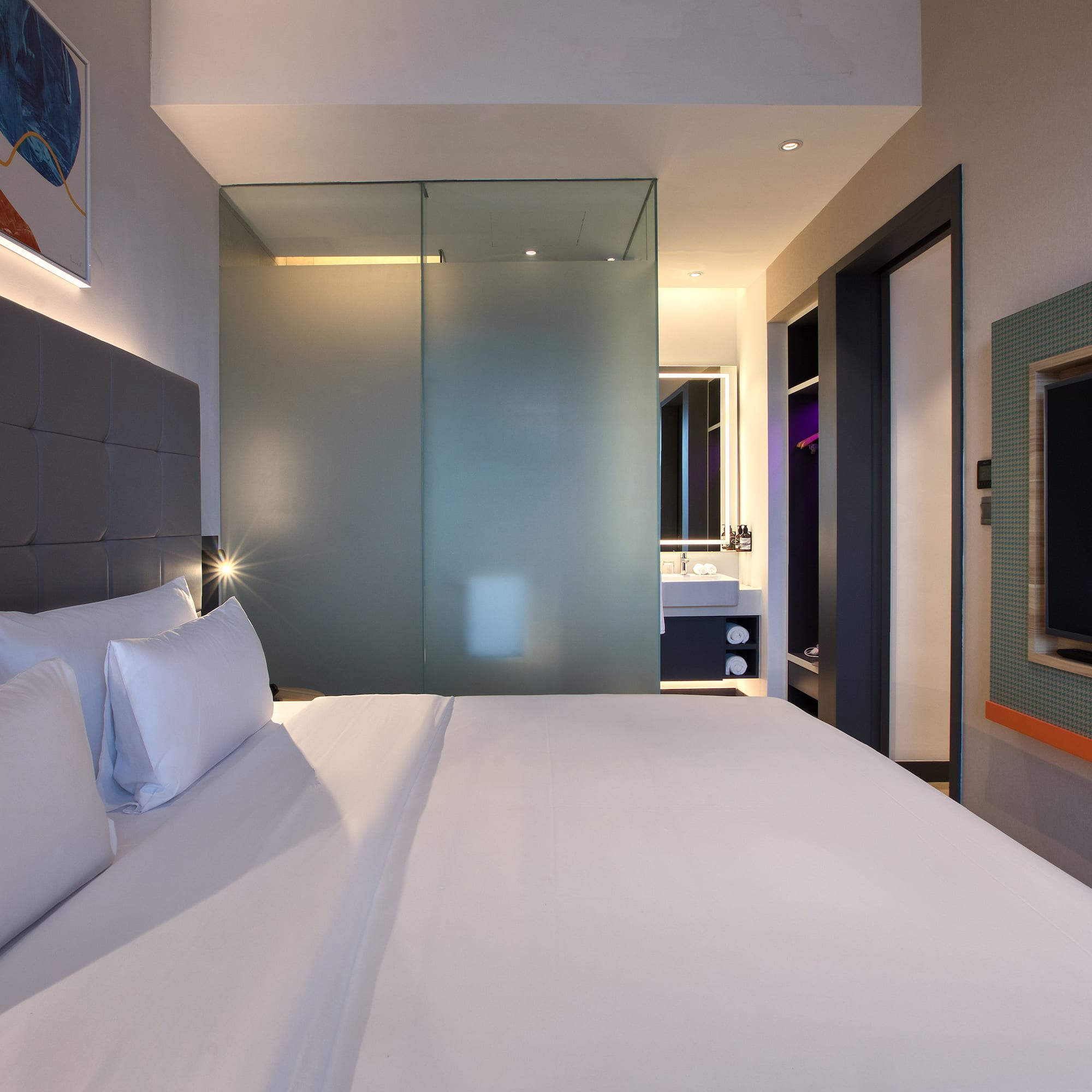 a bed with white sheets and a glass shower door