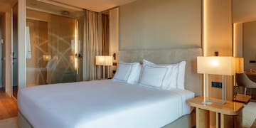 a bed with white sheets and a lamp next to a glass door