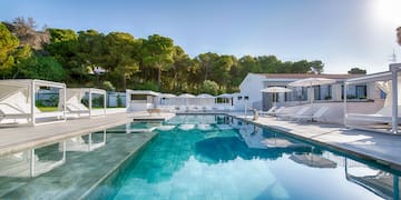 a swimming pool with white buildings and trees in the background