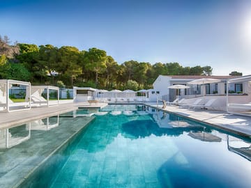 a swimming pool with white buildings and trees in the background