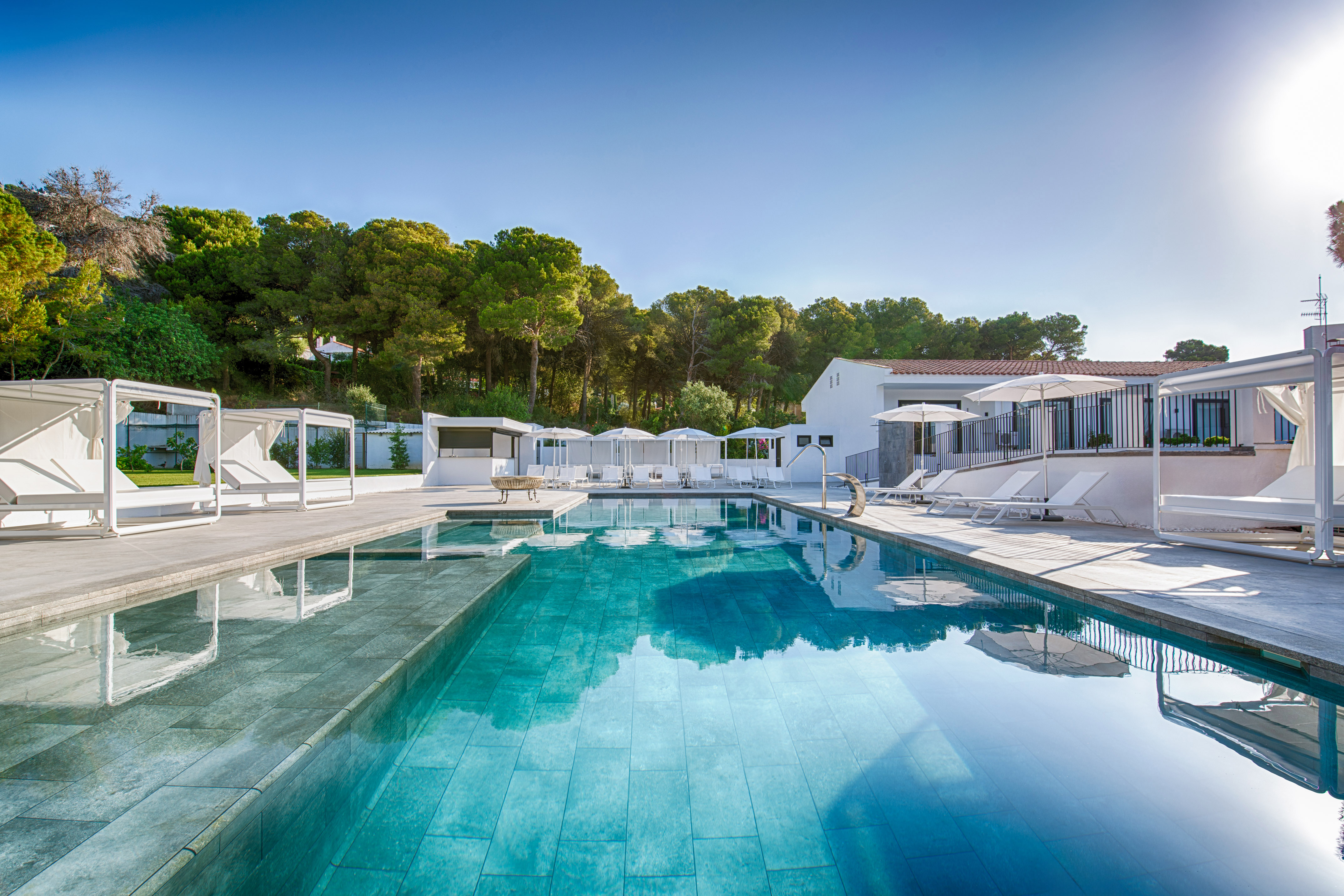 a swimming pool with white buildings and trees in the background