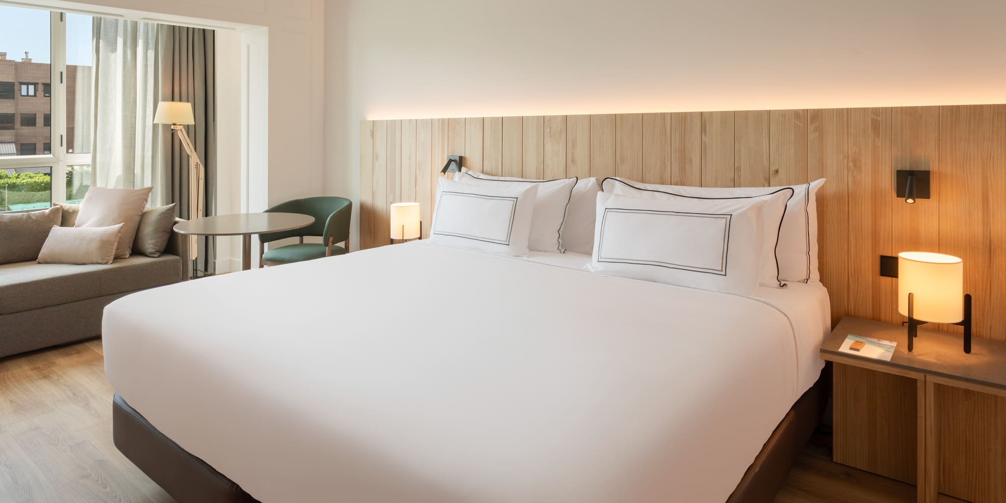 a bed with white sheets and a table and chairs in a room