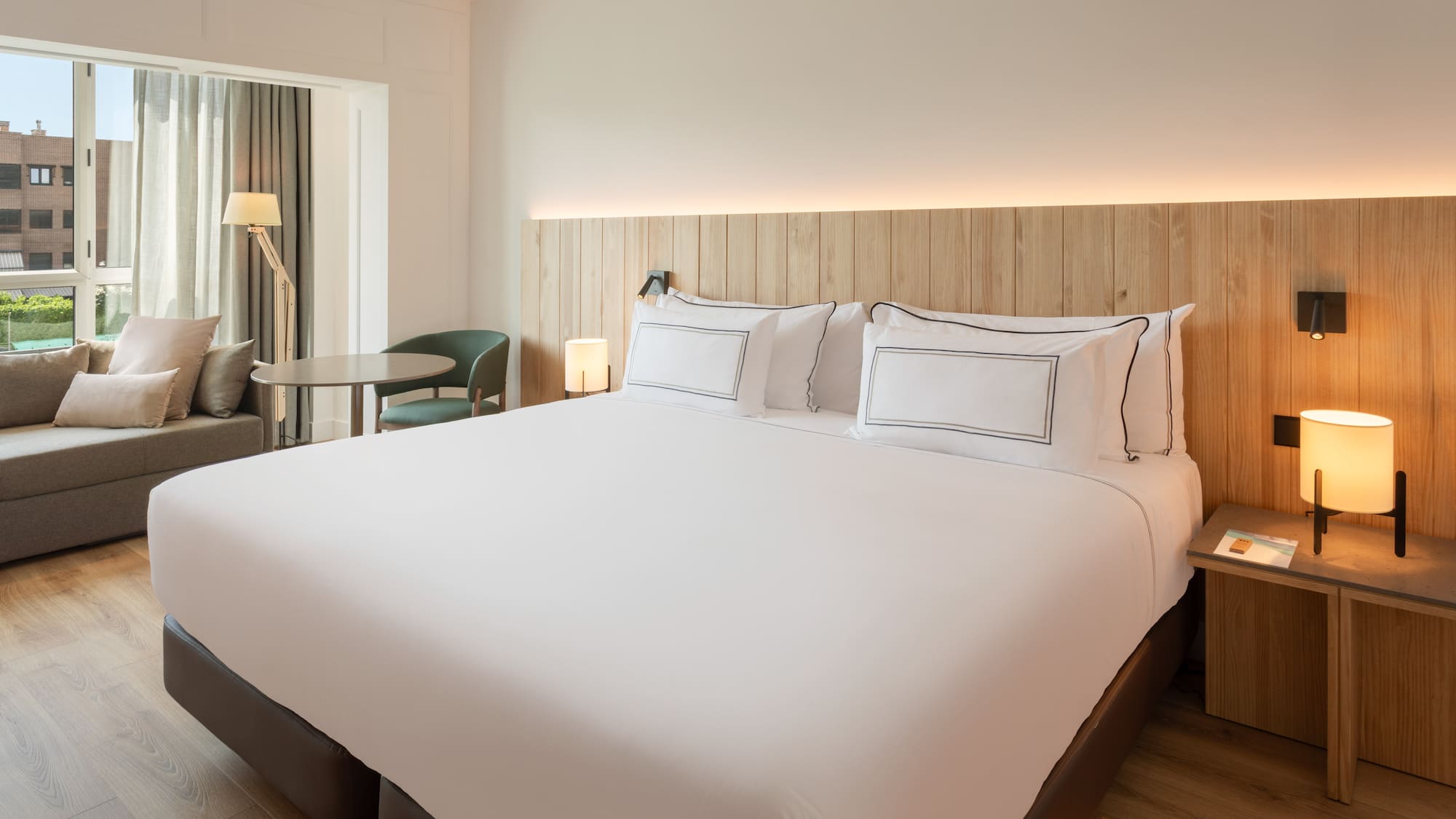 a bed with white sheets and a table and chairs in a room