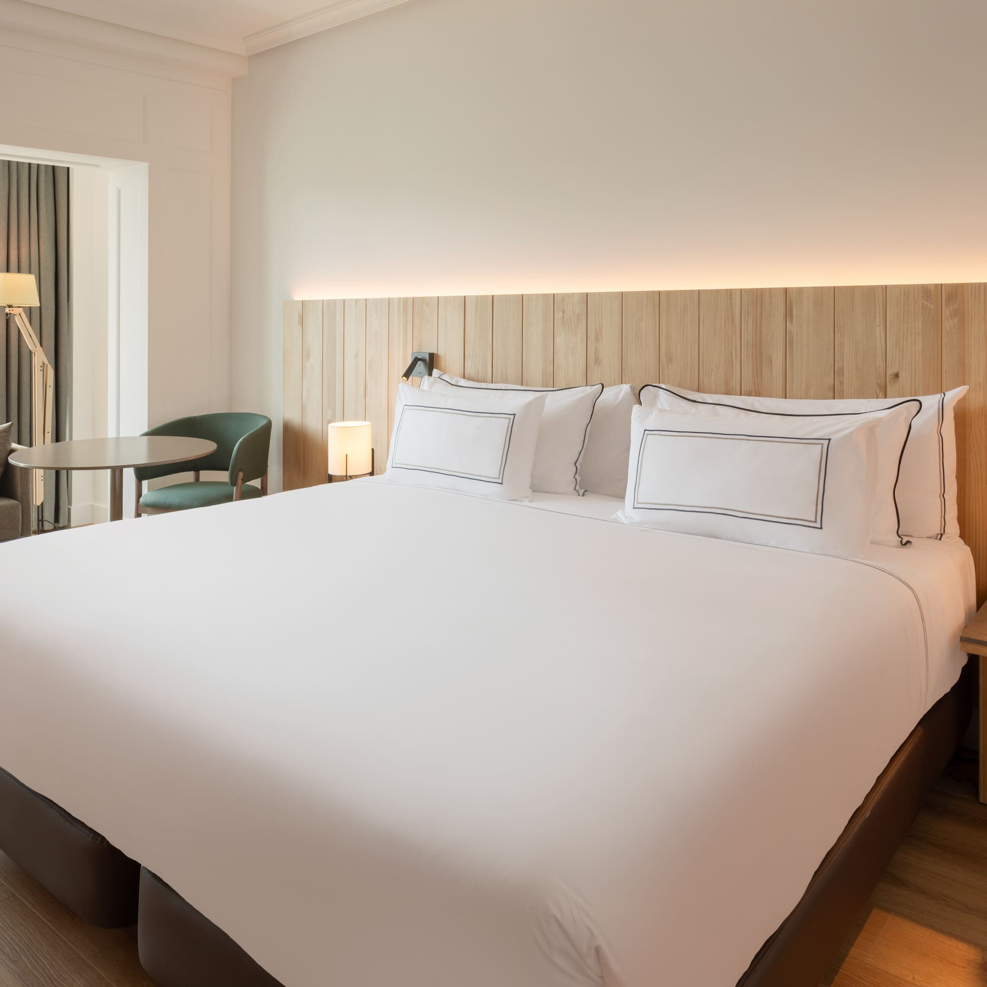 a bed with white sheets and a table and chairs in a room