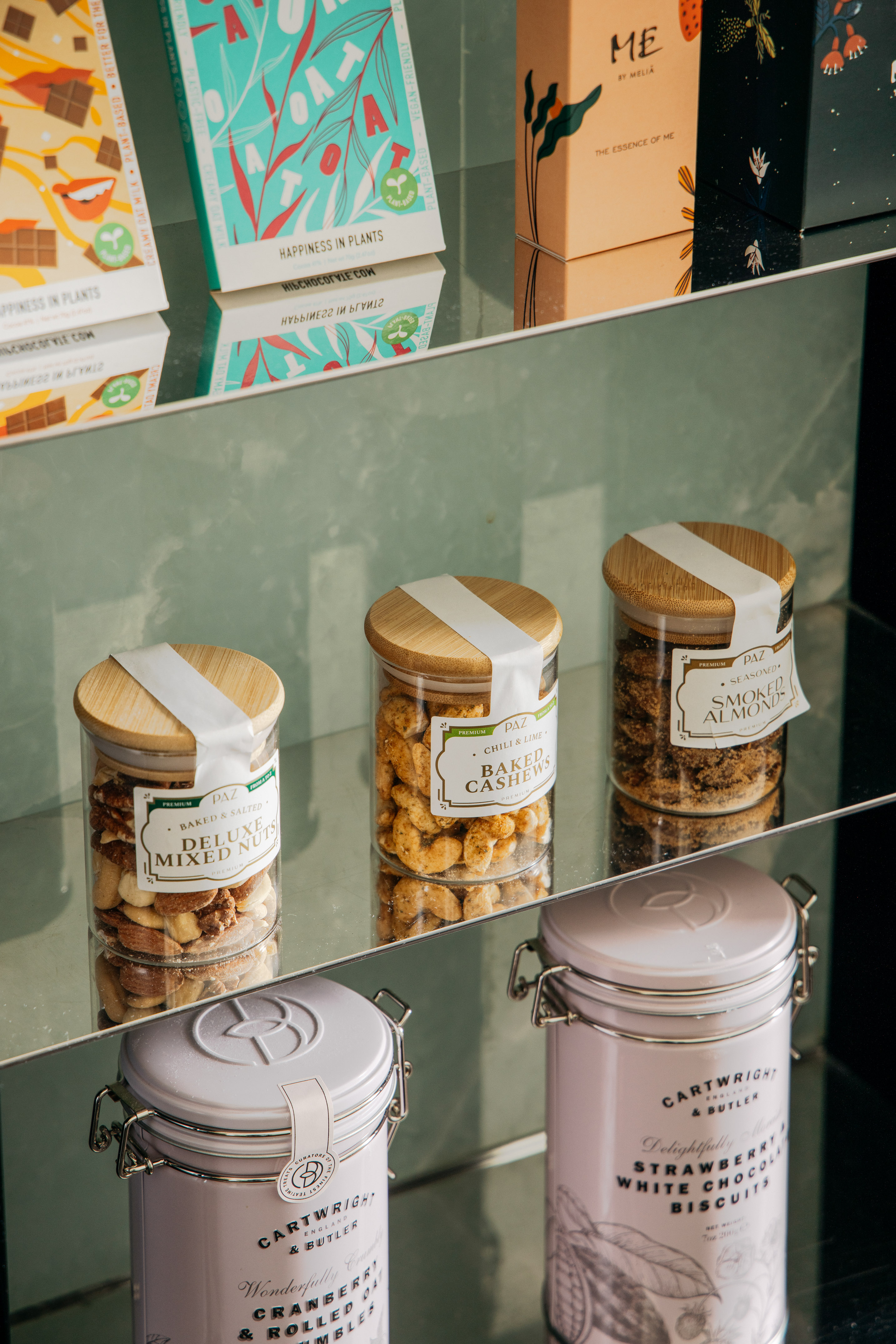 Gourmet nuts, biscuits, and plant-based chocolates displayed on shelves.