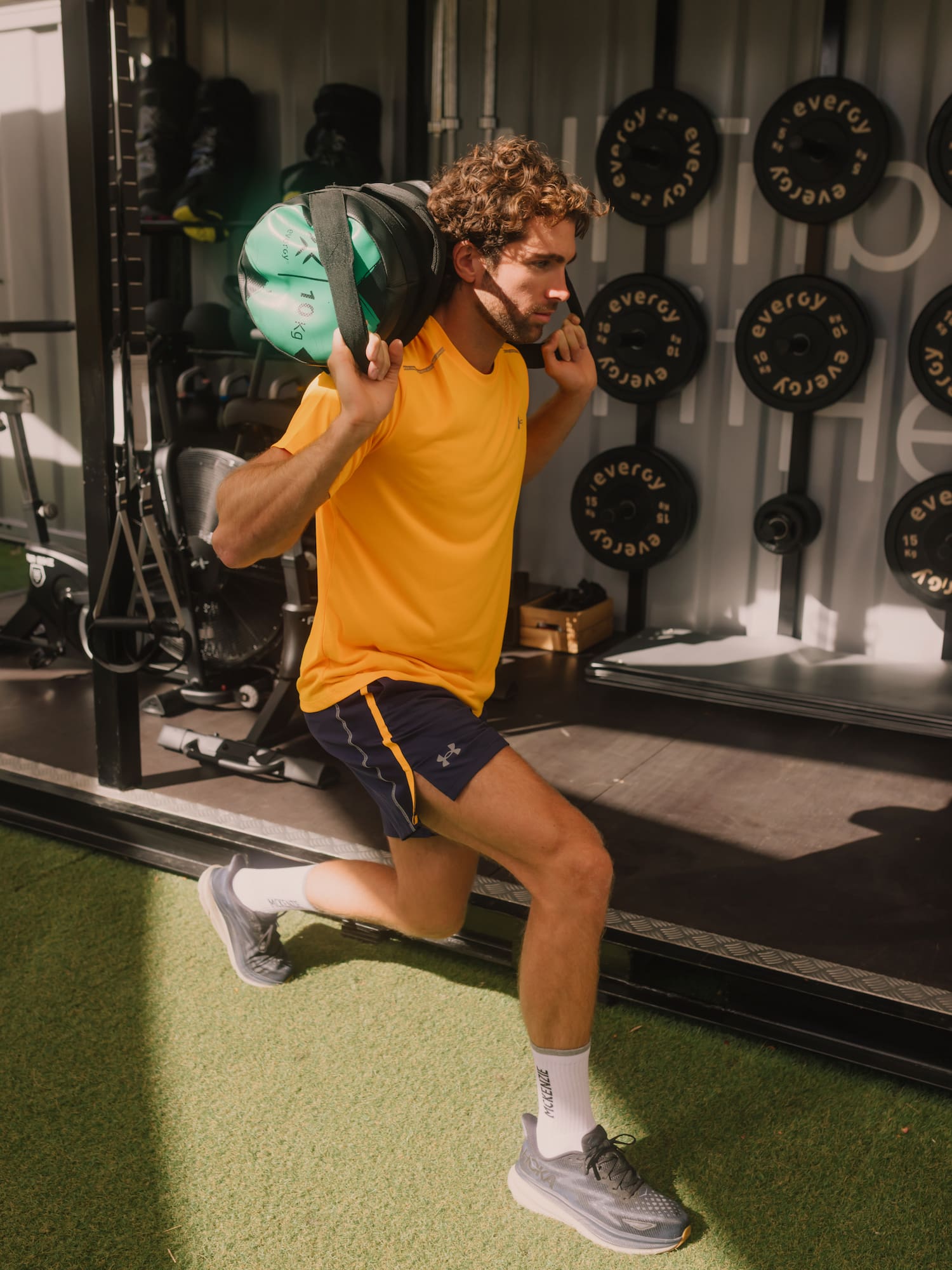 a man in a yellow shirt carrying a weight bag