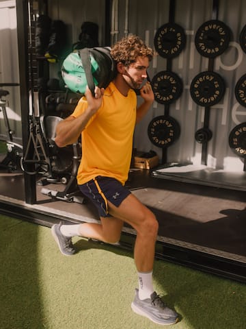a man in a yellow shirt carrying a weight bag