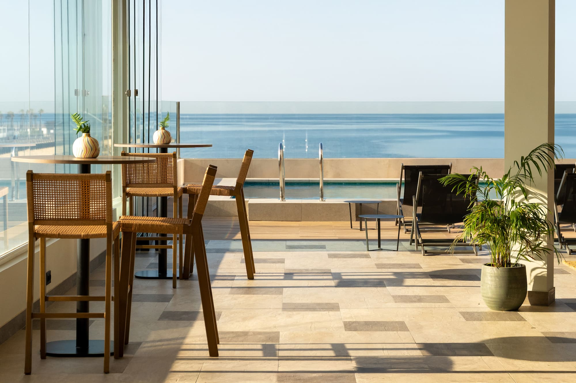 Beachfront resort terrace with outdoor bar seating, swimming pool, and ocean view.