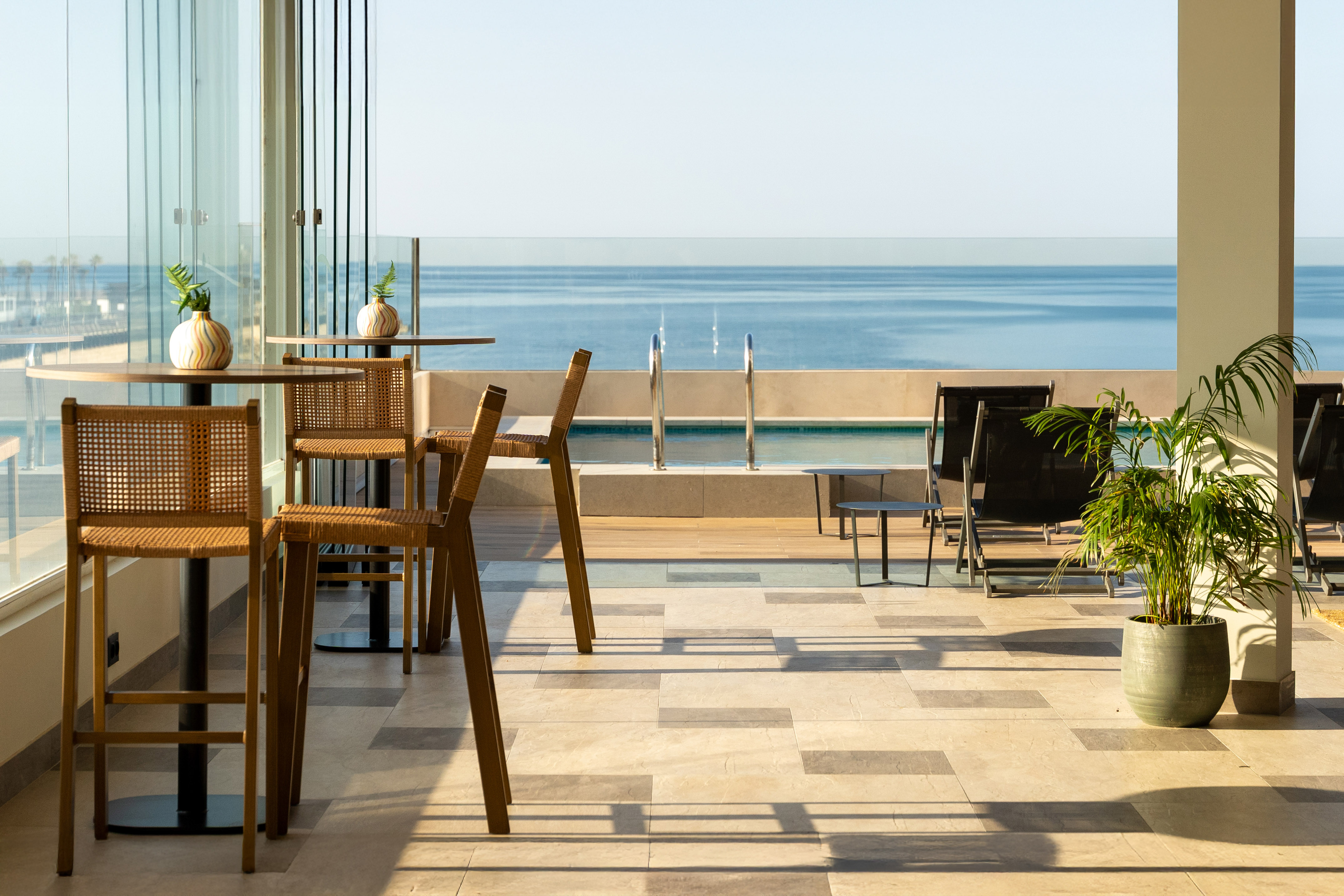 Beachfront resort terrace with outdoor bar seating, swimming pool, and ocean view.