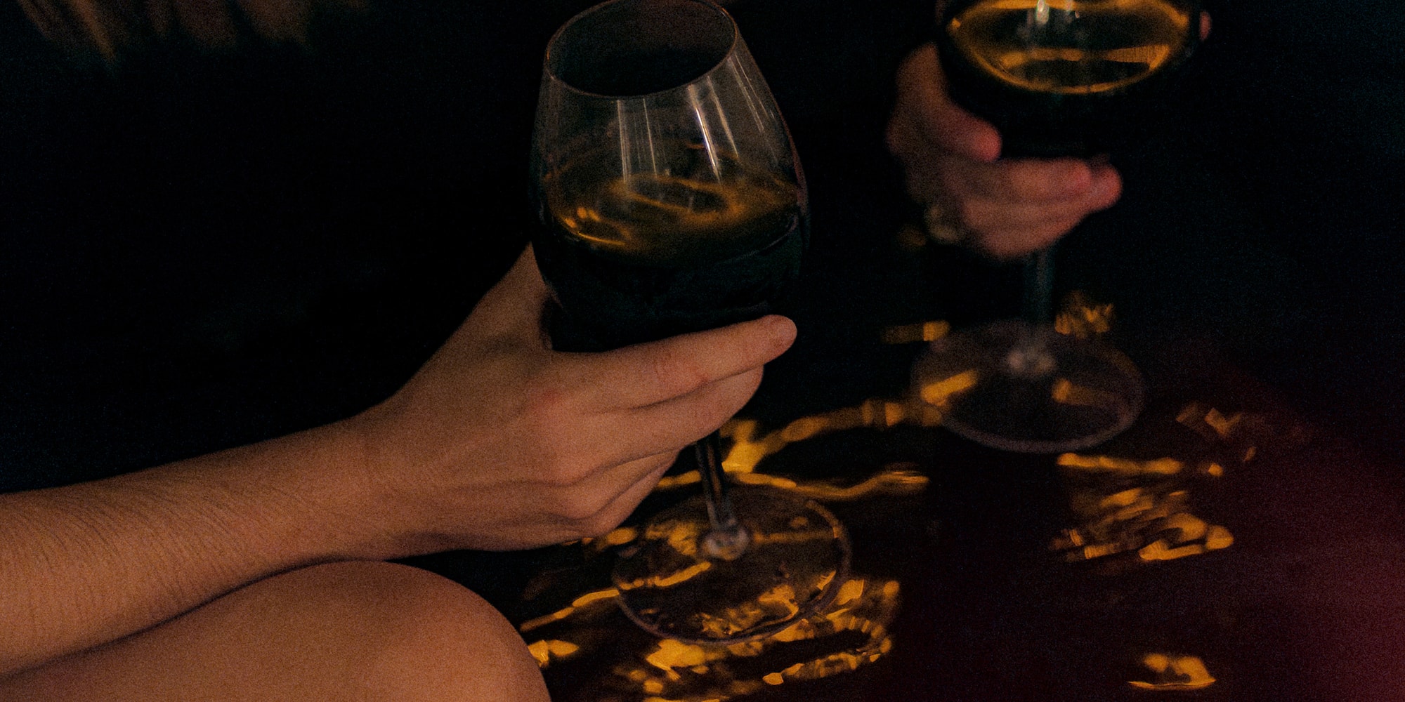 a pair of hands holding wine glasses