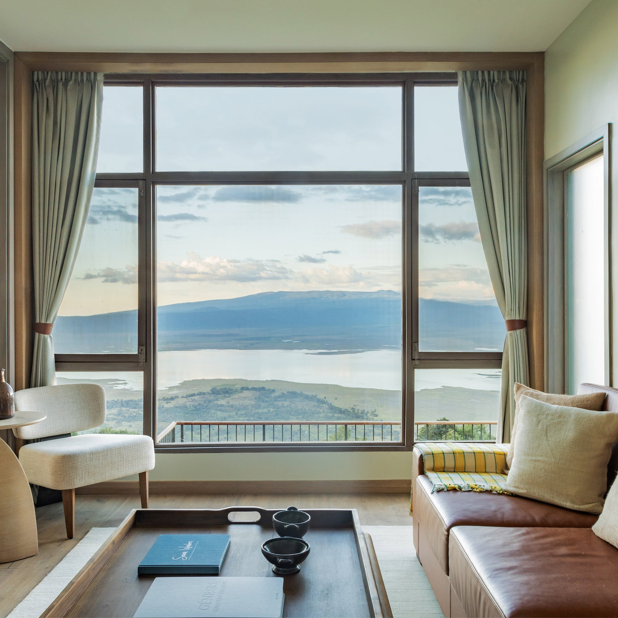 Safari lodge lounge with large window, scenic lake and mountain views.